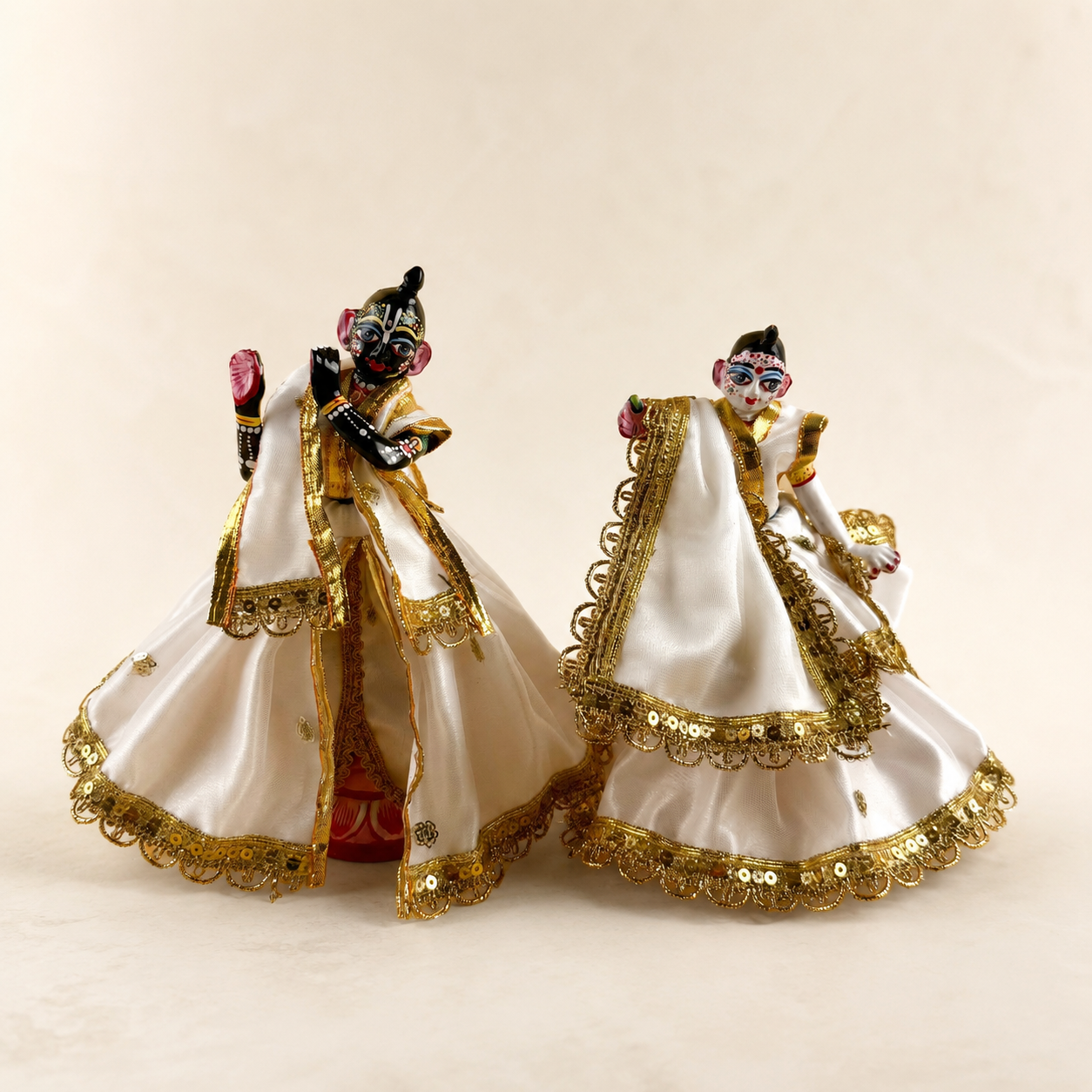 Designer Radha Krishna poshak set in white and gold displayed on deity idols