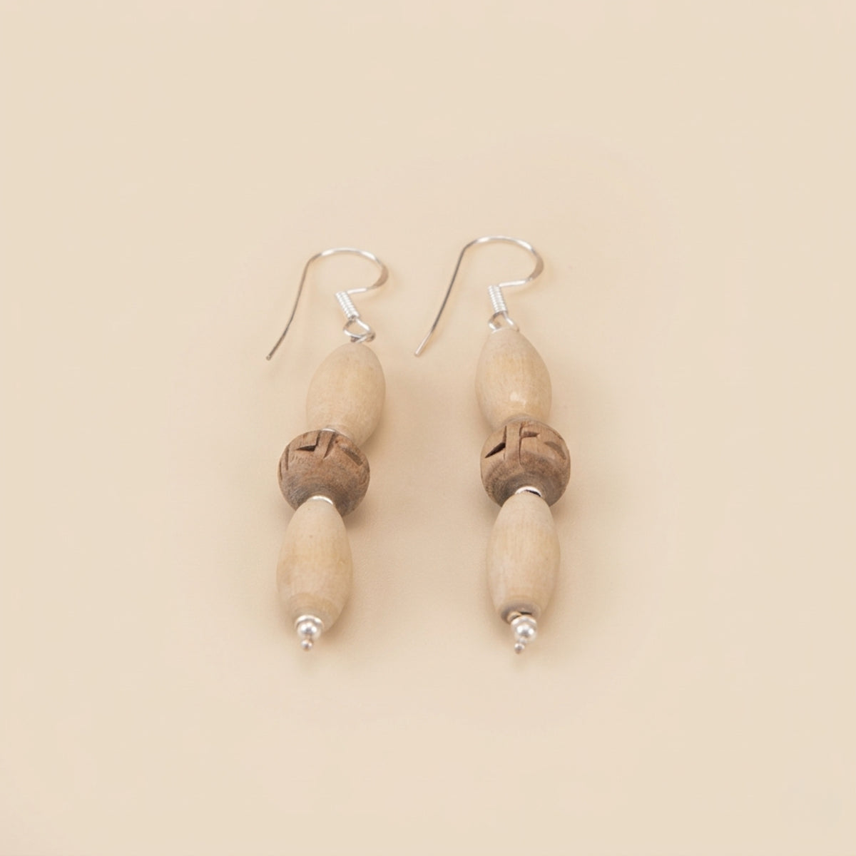 Close up flat lay of designer silver dangle earrings featuring authentic Tulsi wood beads
