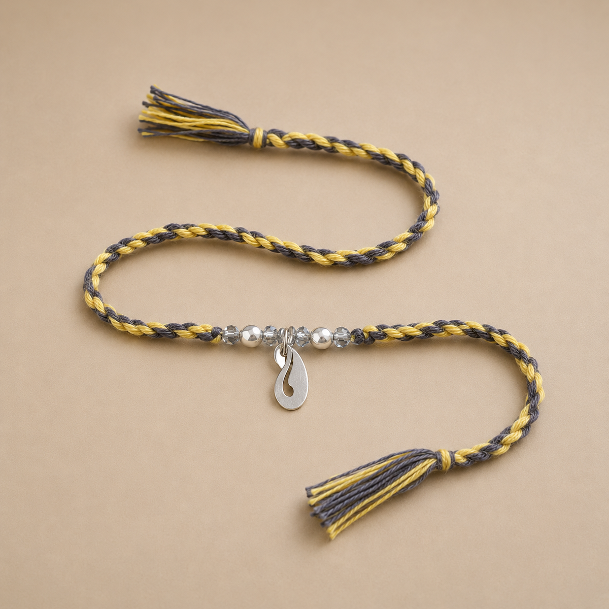 Designer silver peacock motif rakhi with black and yellow braided thread and tassels
