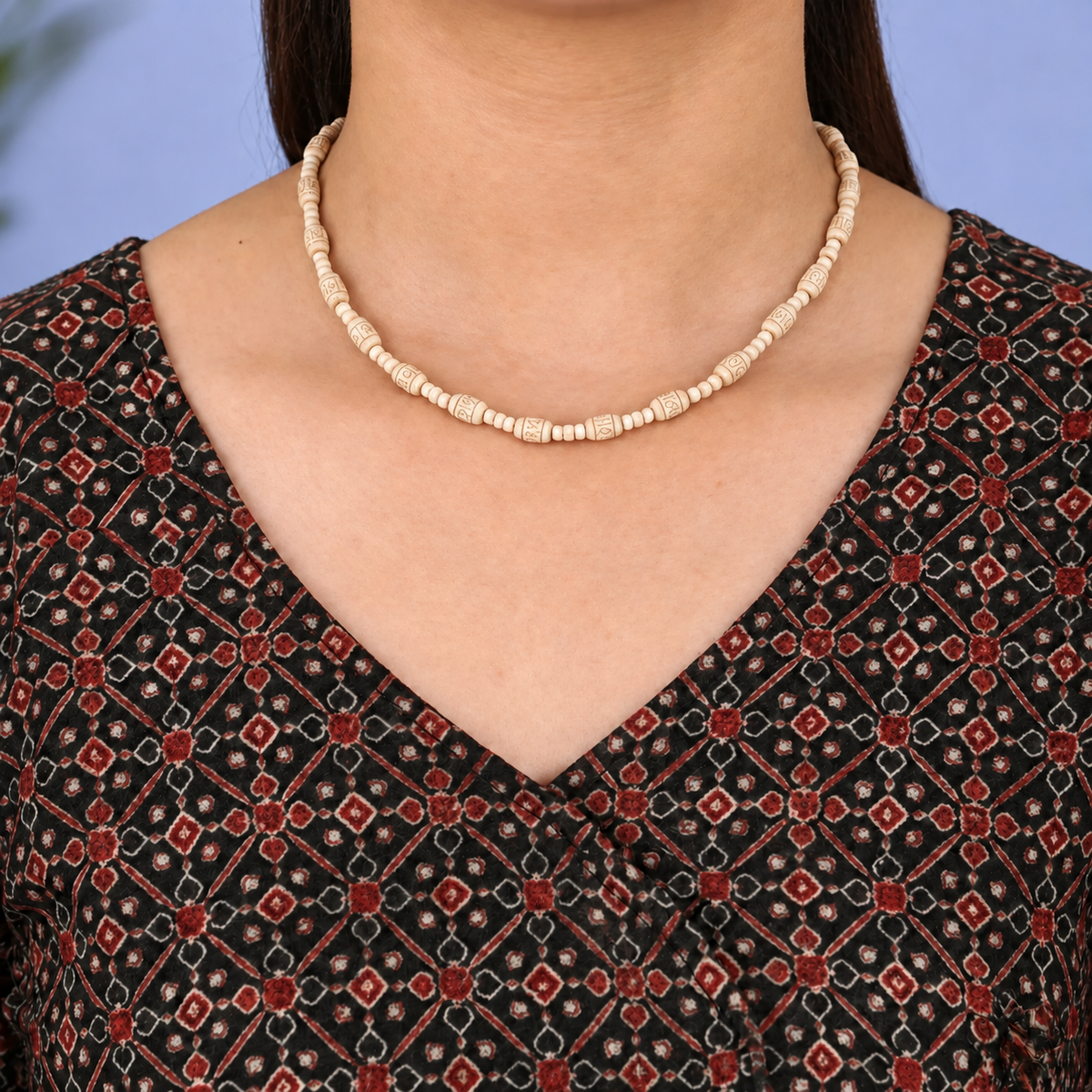 Tulsi kanthi mala with engraved barrel beads and small disc spacers worn with a black and red printed kurta.