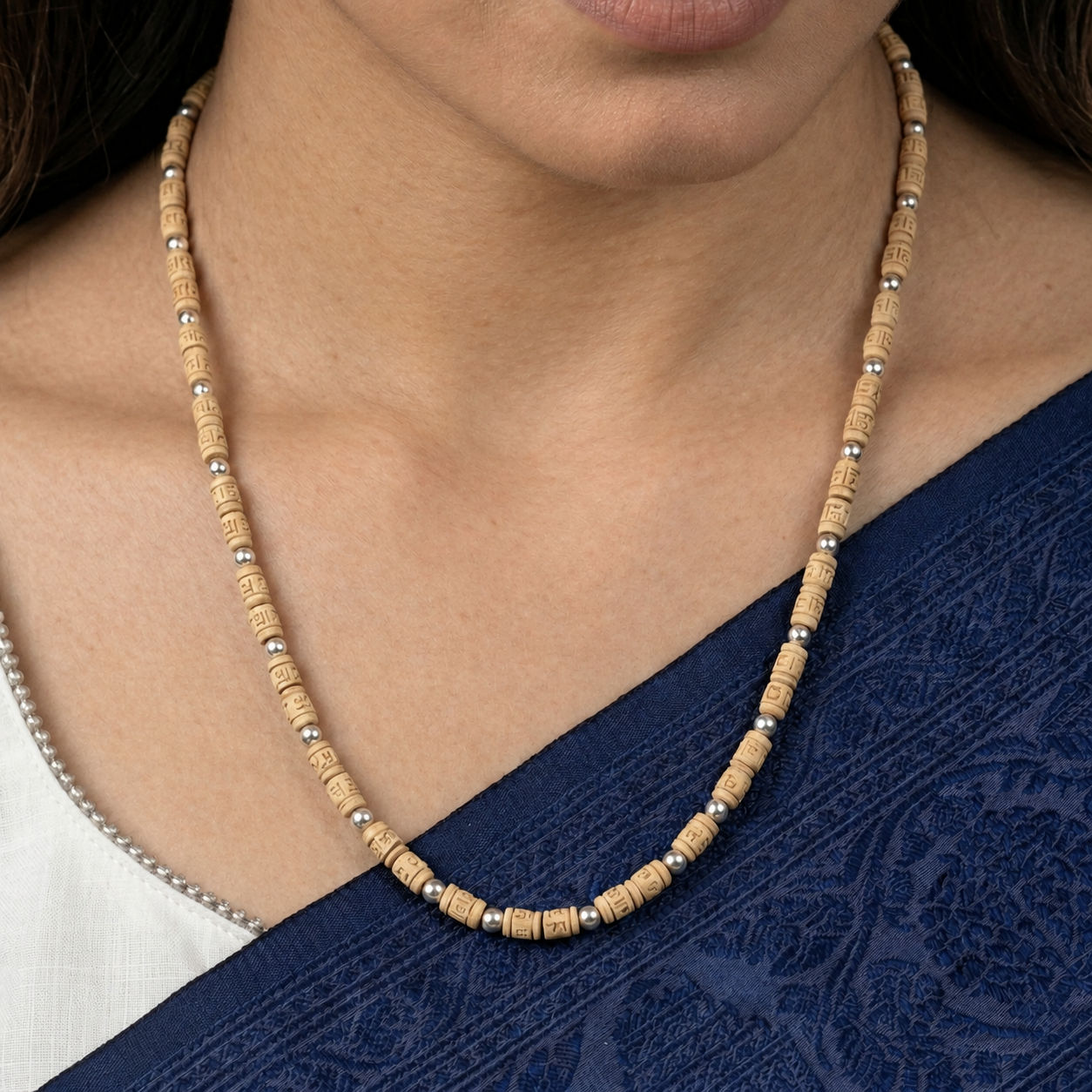 Tulsi mala with engraved cylindrical wooden beads and round silver-toned spacers worn with a navy saree.