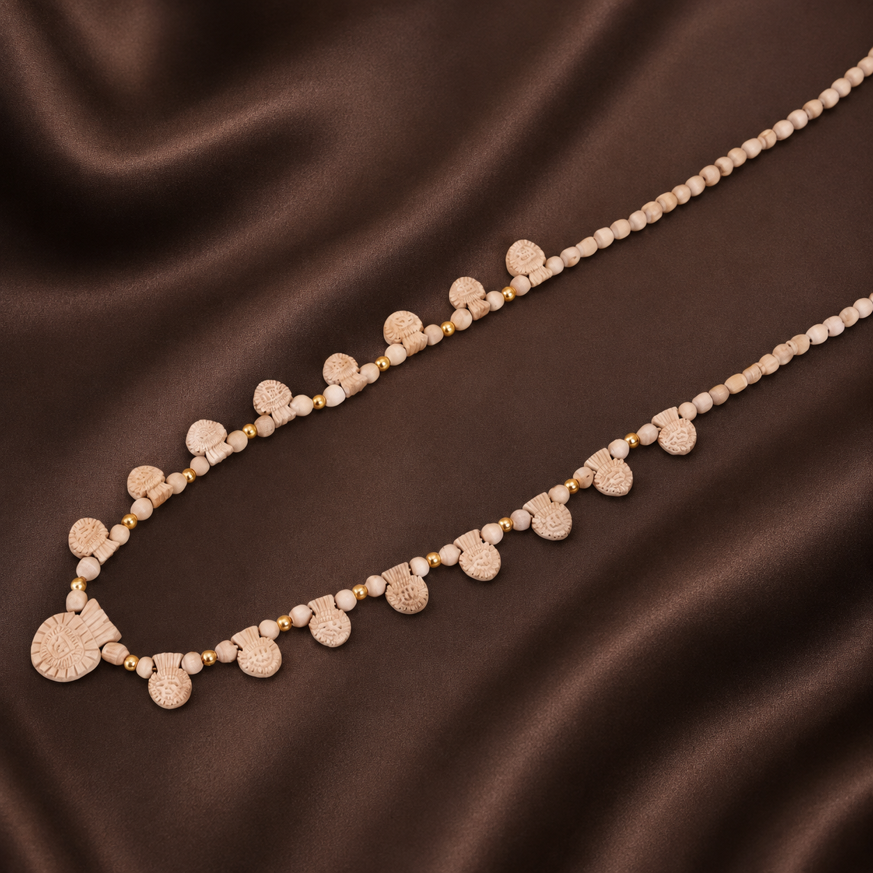 Gold Tulsi pendant mala necklace displayed beautifully on a traditional silk cloth