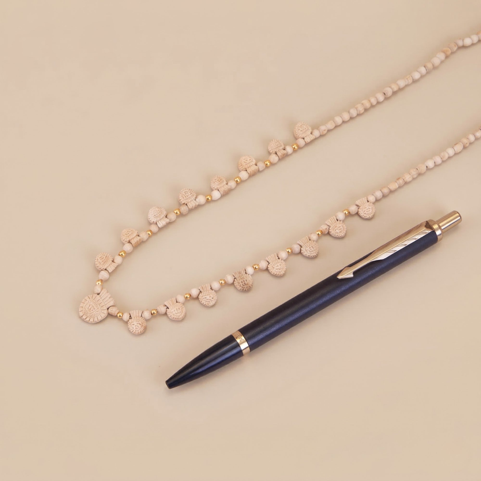 Close up flat lay of an authentic gold Tulsi pendant necklace and accessories