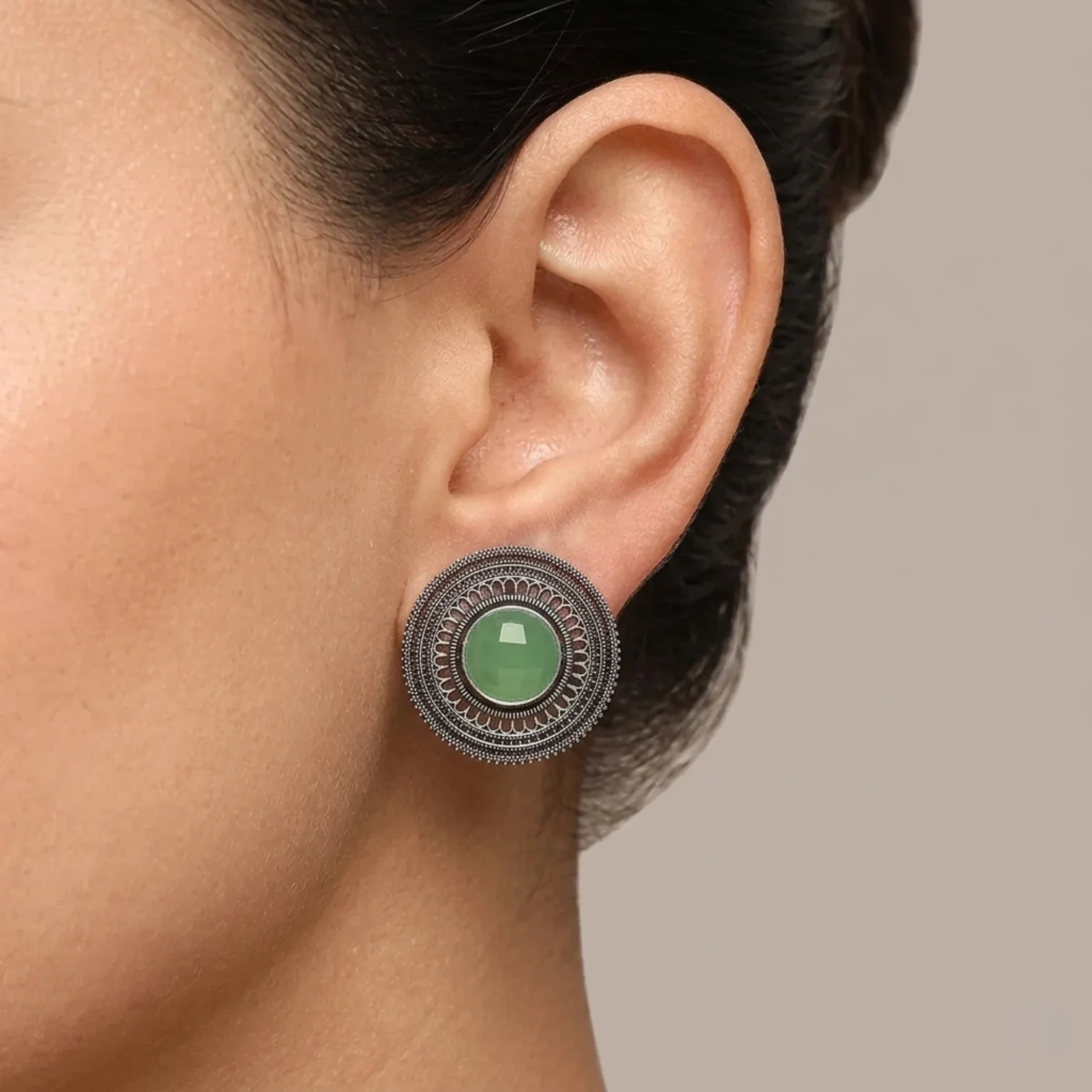 Green oxidised metal imitation stud earring worn on the ear