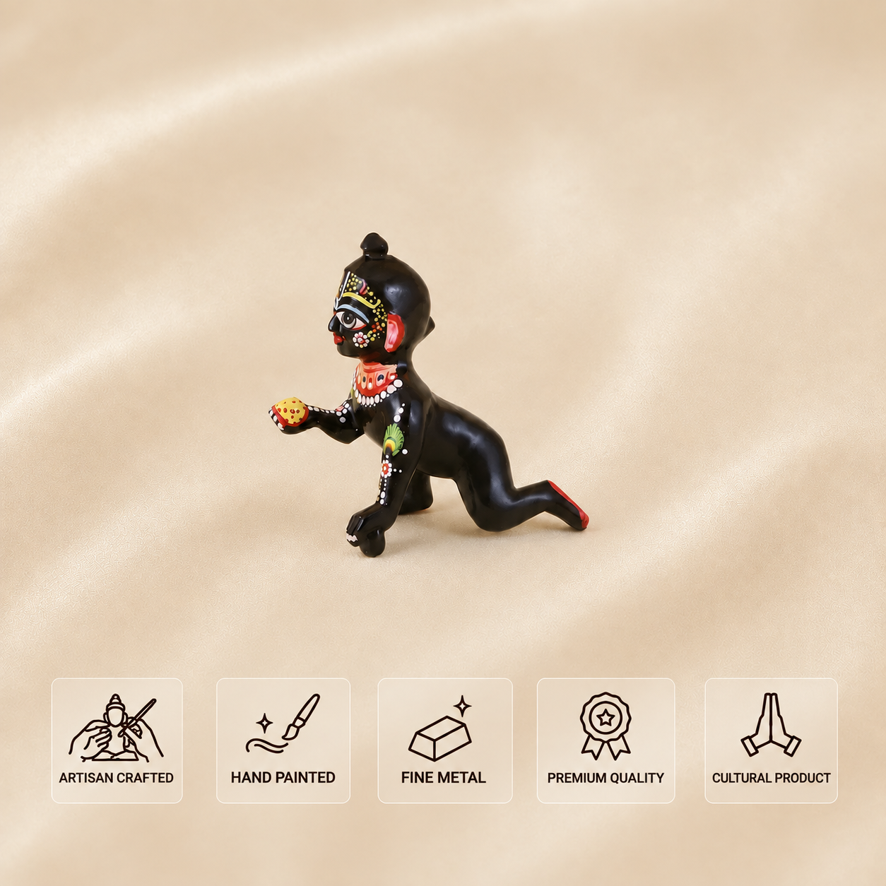 Side view of a hand-painted black Laddu Gopal idol in a crawling pose, holding a laddu.