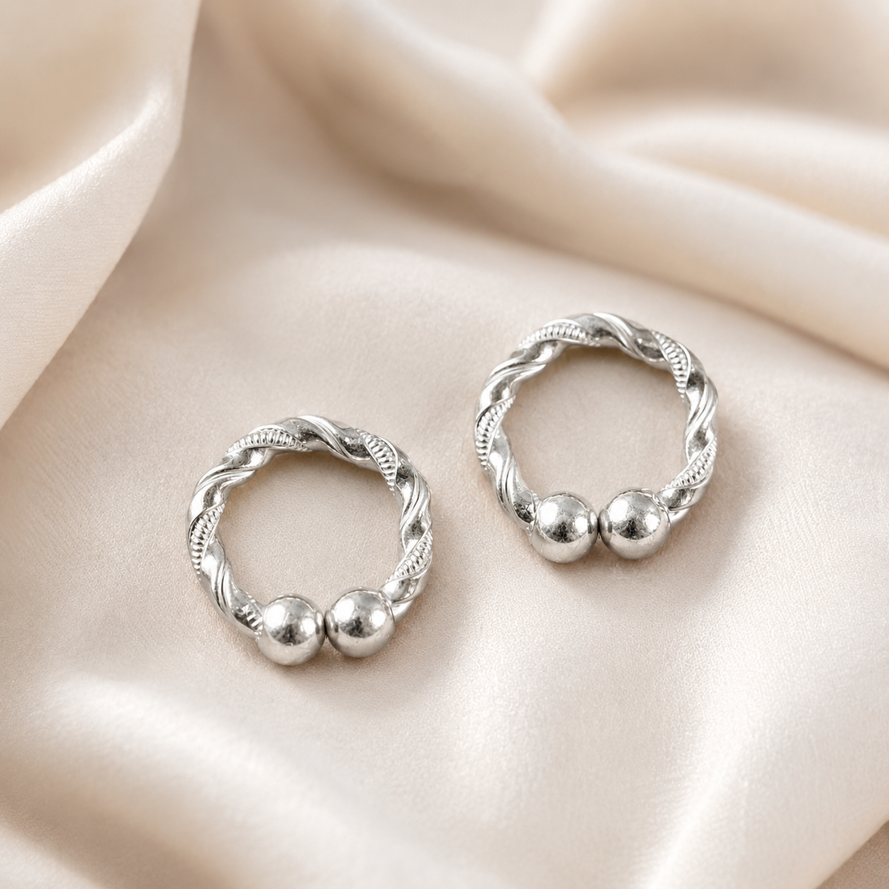 Pair of handcrafted silver kada for deities displayed on soft cream silk backdrop