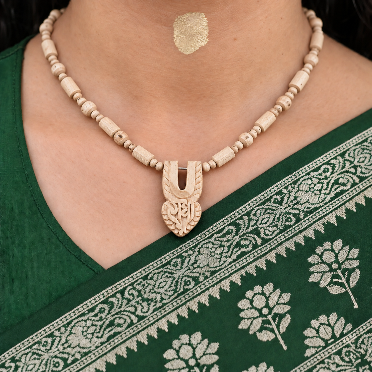 Woman wearing a handmade Tulsi wood Kanthi Mala with natural wooden beads and carved Radha pendant, styled with a traditional green saree.