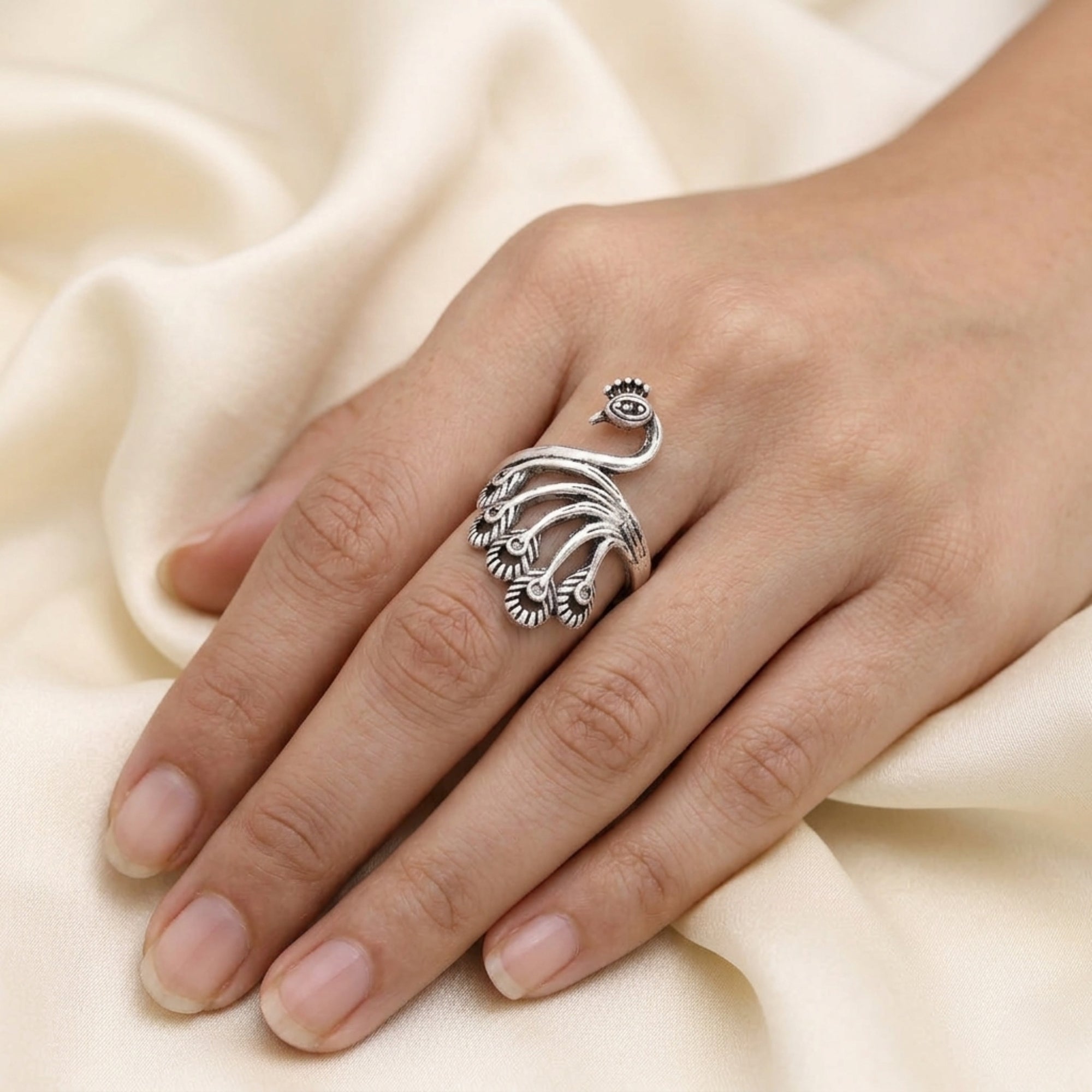 Woman hand wearing handmade oxidized metal peacock ring with intricate feather detail