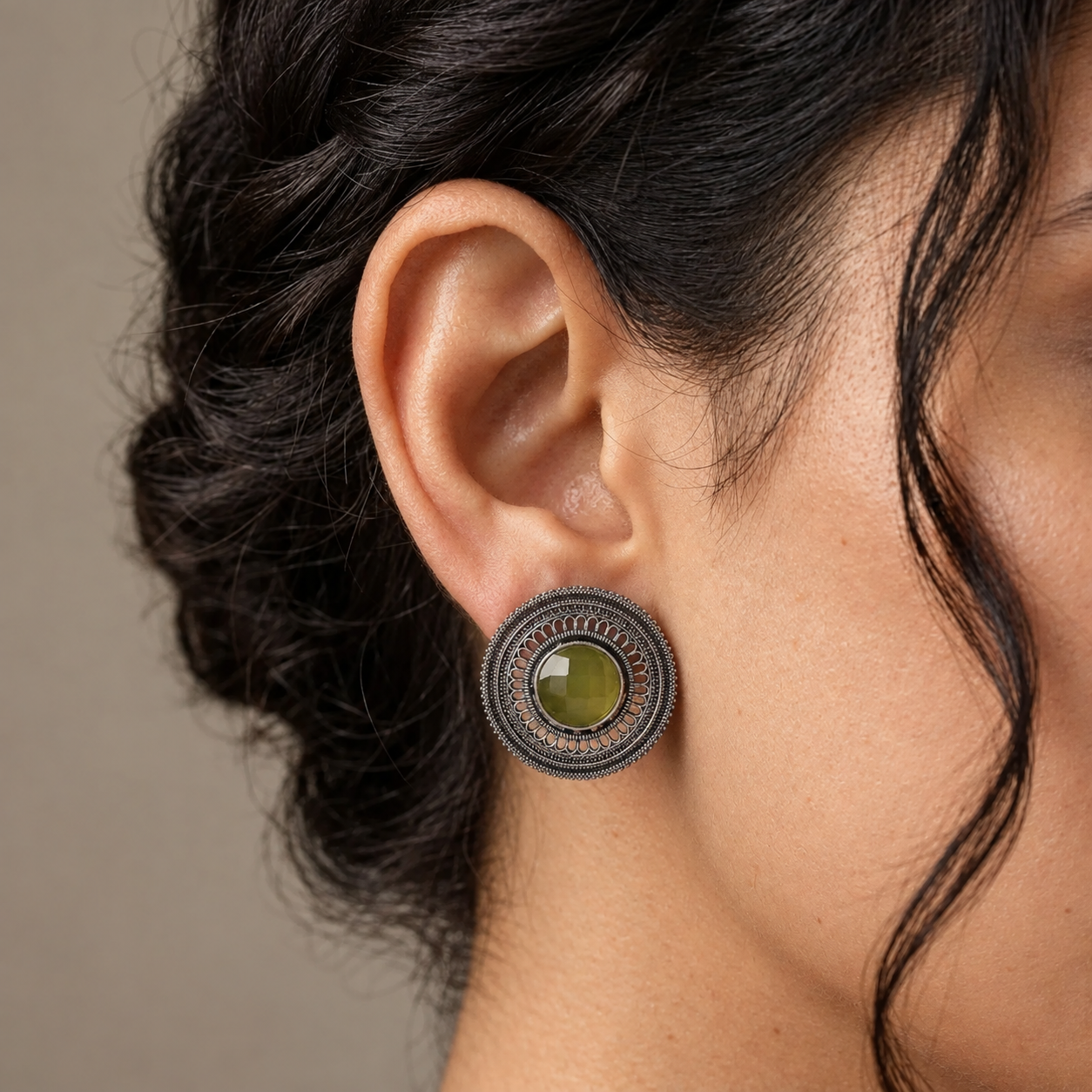 Model wearing a round imitation filigree earring with an olive-green centre stone