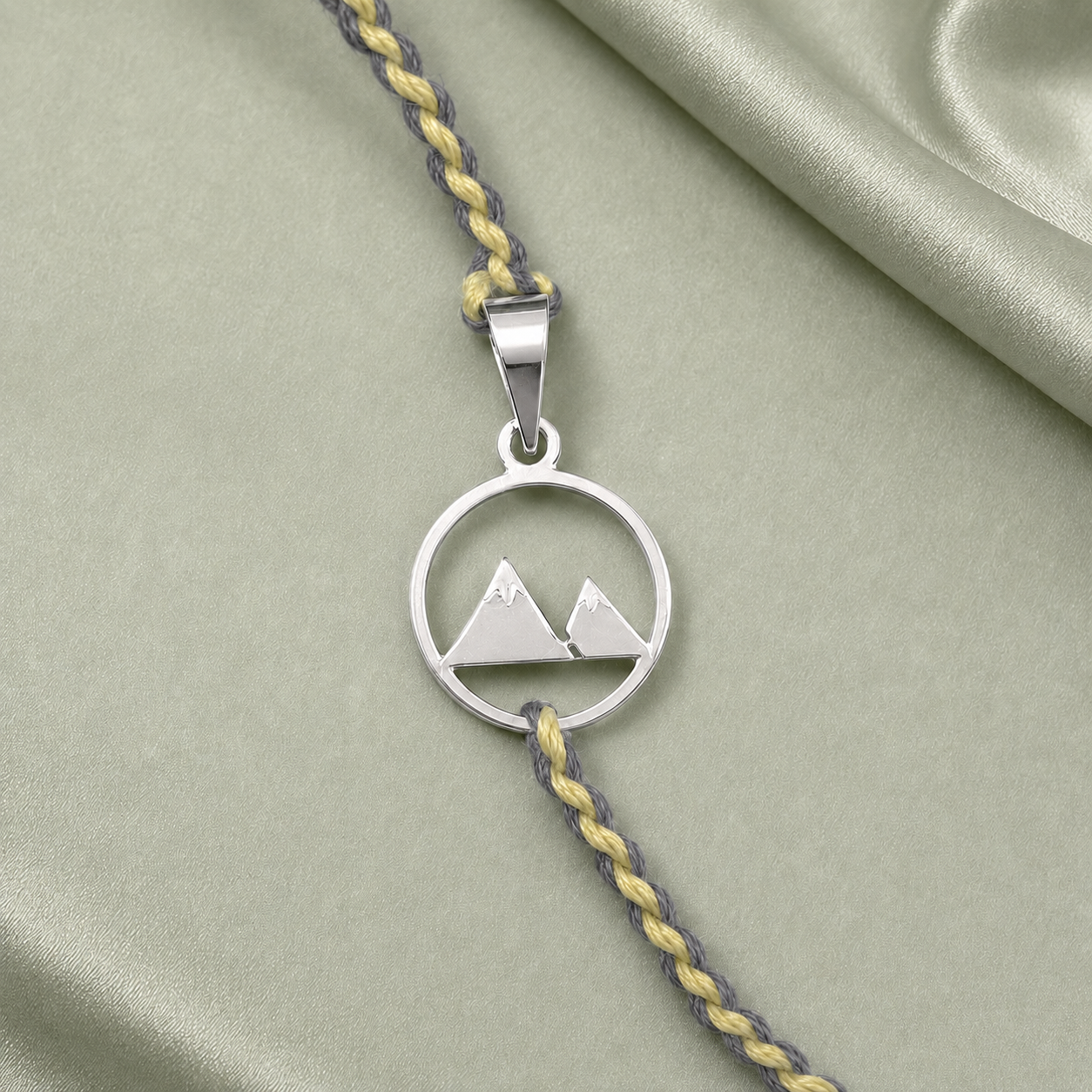 Close up view of circular twin mountain peaks charm in 925 sterling silver