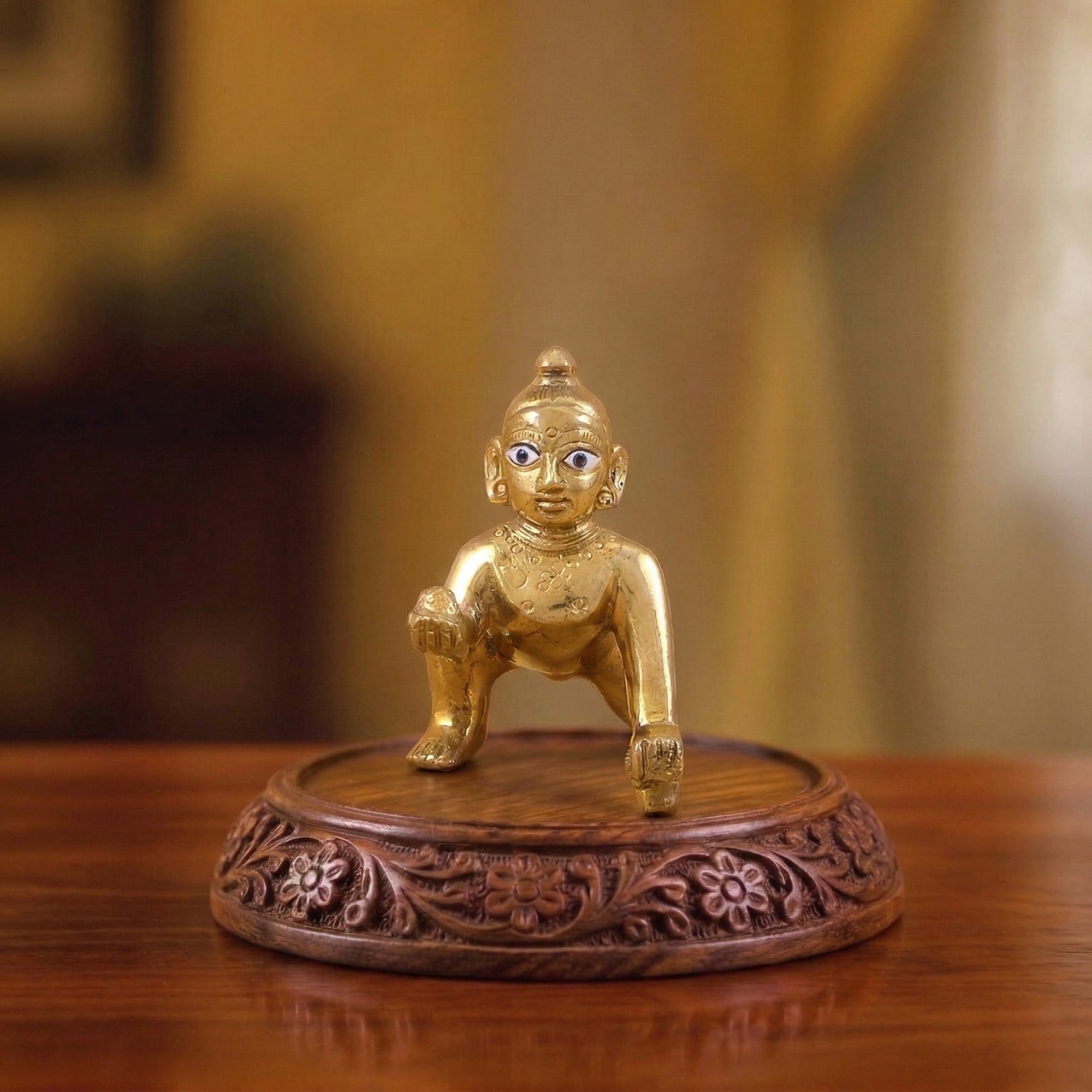 Golden finish plain Laddu Gopal Ashtadhatu idol with big eyes displayed on a wooden temple altar