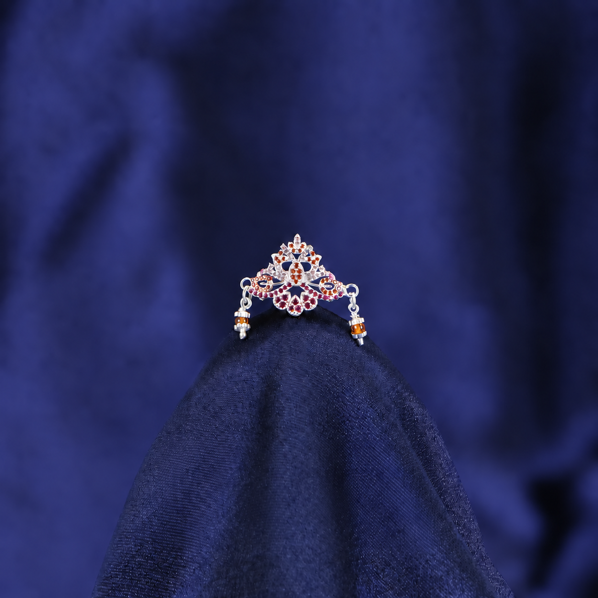 Ornate silver-tone Laddu Gopal mukut with red and orange stones and dangling amber side beads