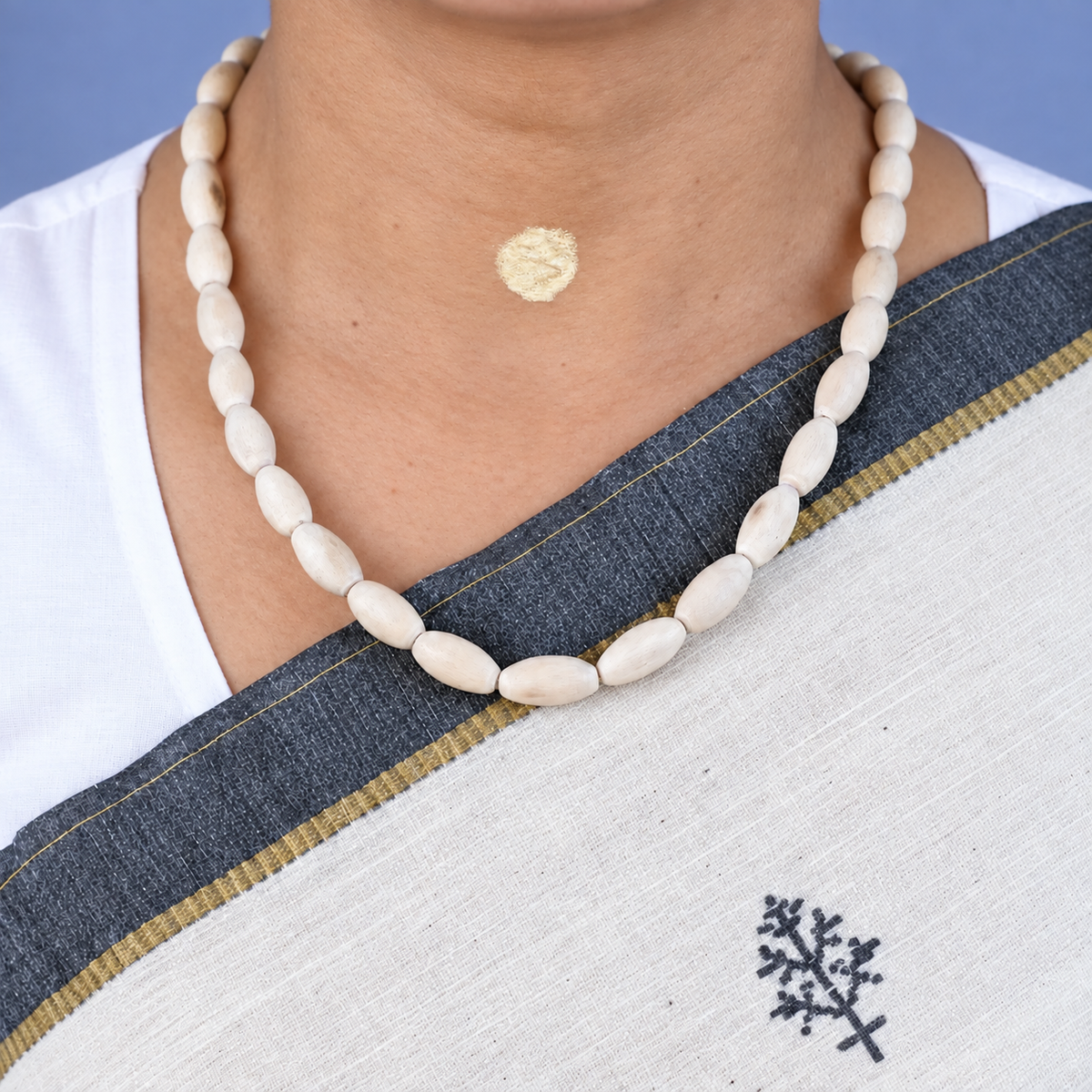 Tulsi kanthi mala with large oval wooden beads worn with a white saree with a dark border.