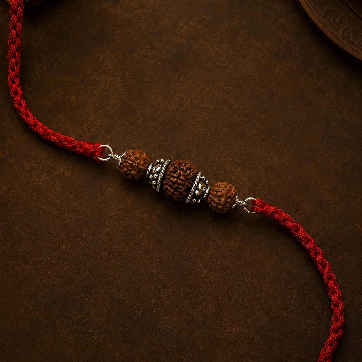 Close up view of 925 pure silver capped three Rudraksha beads on red braided thread