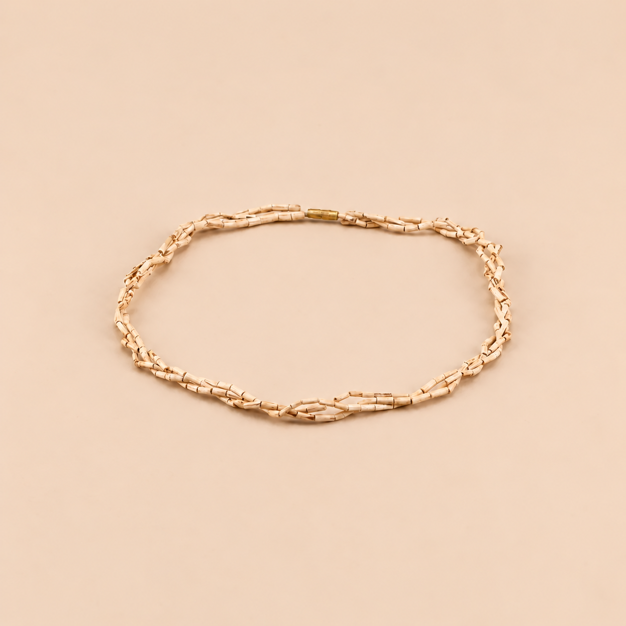 Multi-strand Tulsi bead mala with a gold clasp arranged on a peach background.