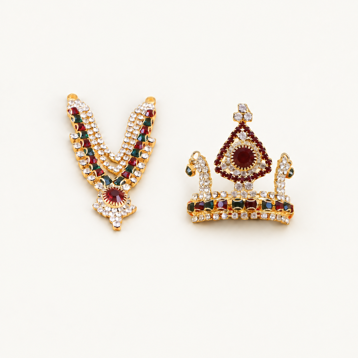 Gold-toned idol necklace and matching crown with red, green and clear stones on an off-white background.