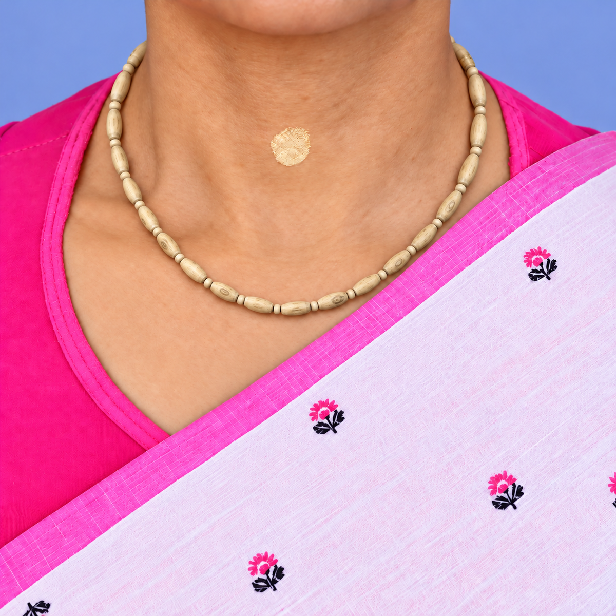 Woman wearing a natural Tulsi wood Kanthi Mala with elongated oval beads, small round wooden spacers and visible wood grain, styled with a pink and white saree.