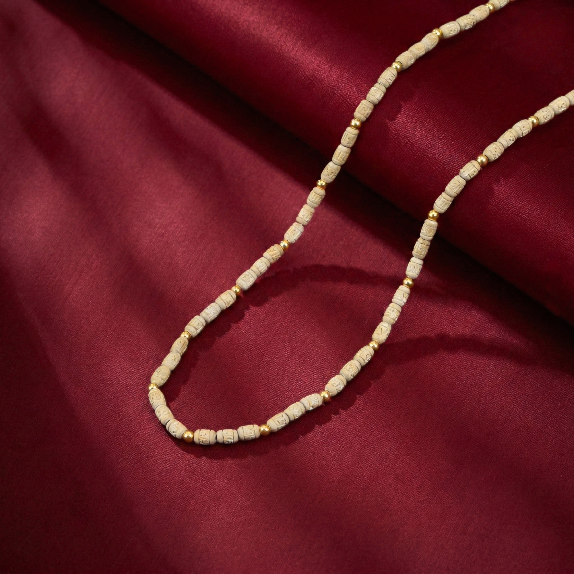 Original gold Tulsi Kanthi Mala necklace displayed on a traditional red silk cloth