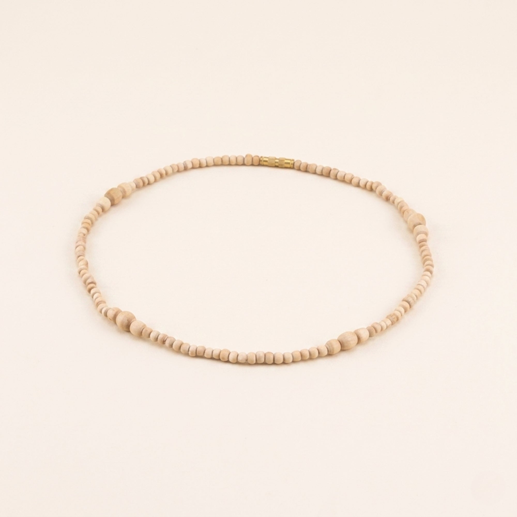 Close up flat lay of a handmade Tulsi bead necklace featuring smooth oval shaped wood beads
