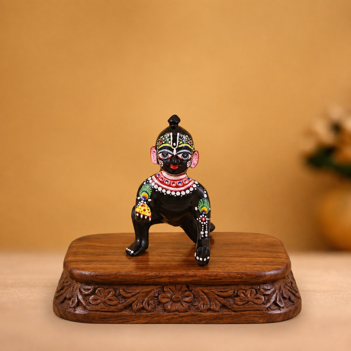 Hand-painted black Laddu Gopal idol with colourful peacock-feather detailing and laddu