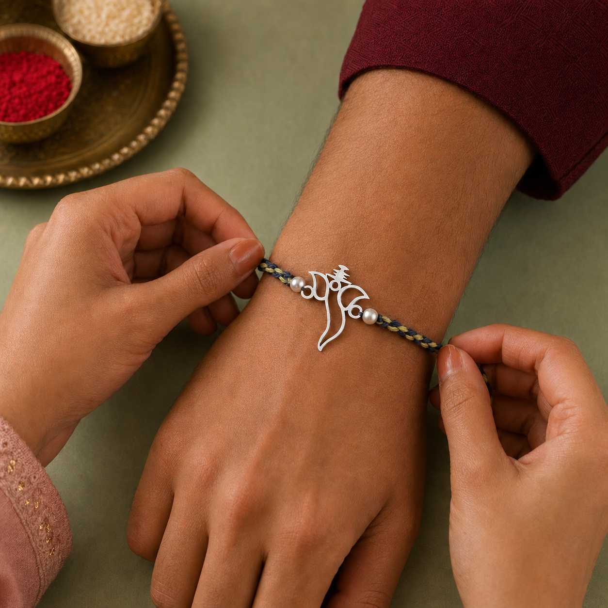 Hands tying original 925 pure silver Ganesha rakhi bracelet on brother wrist for Raksha Bandhan
