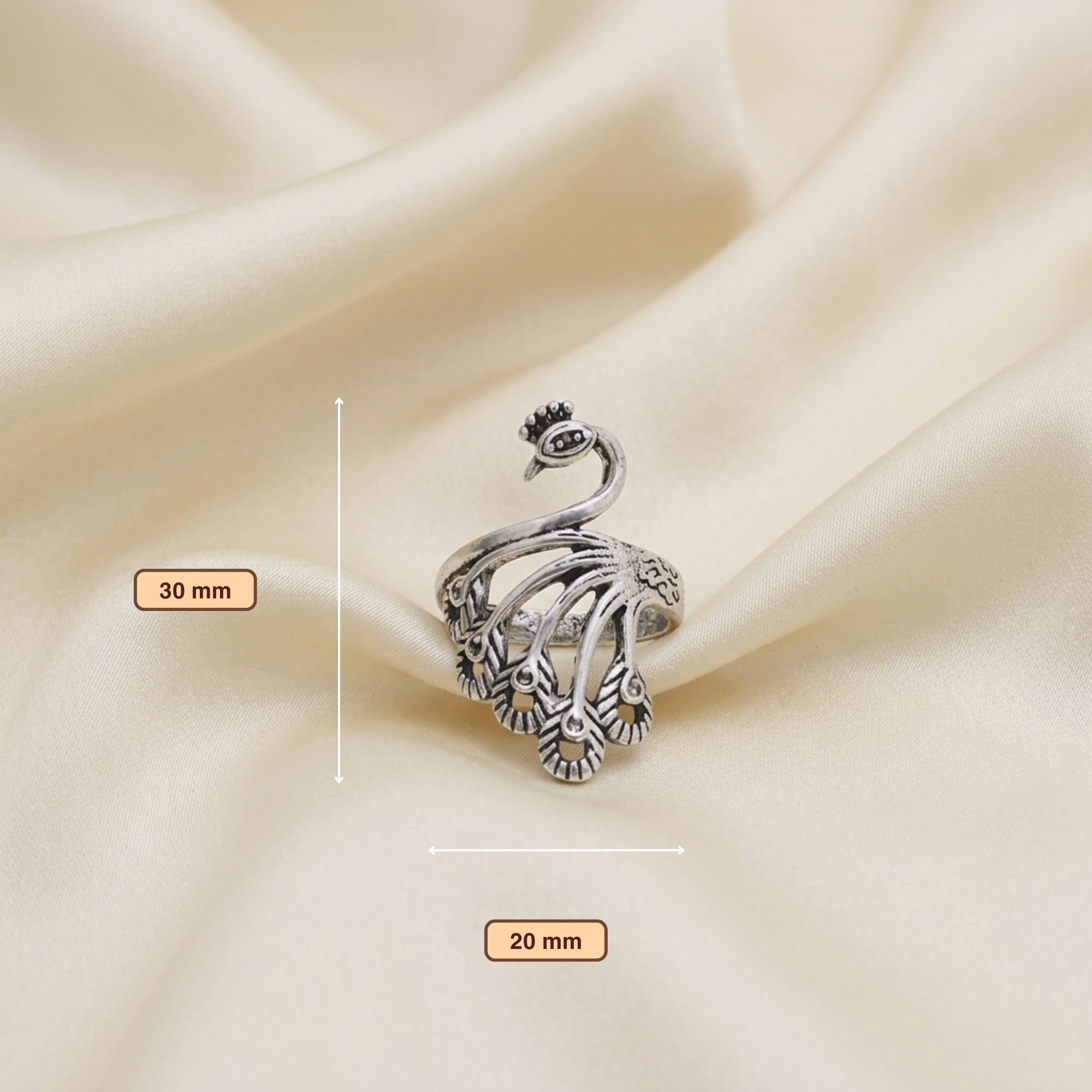 Dimensions of oxidized metal peacock statement ring on cream satin cloth