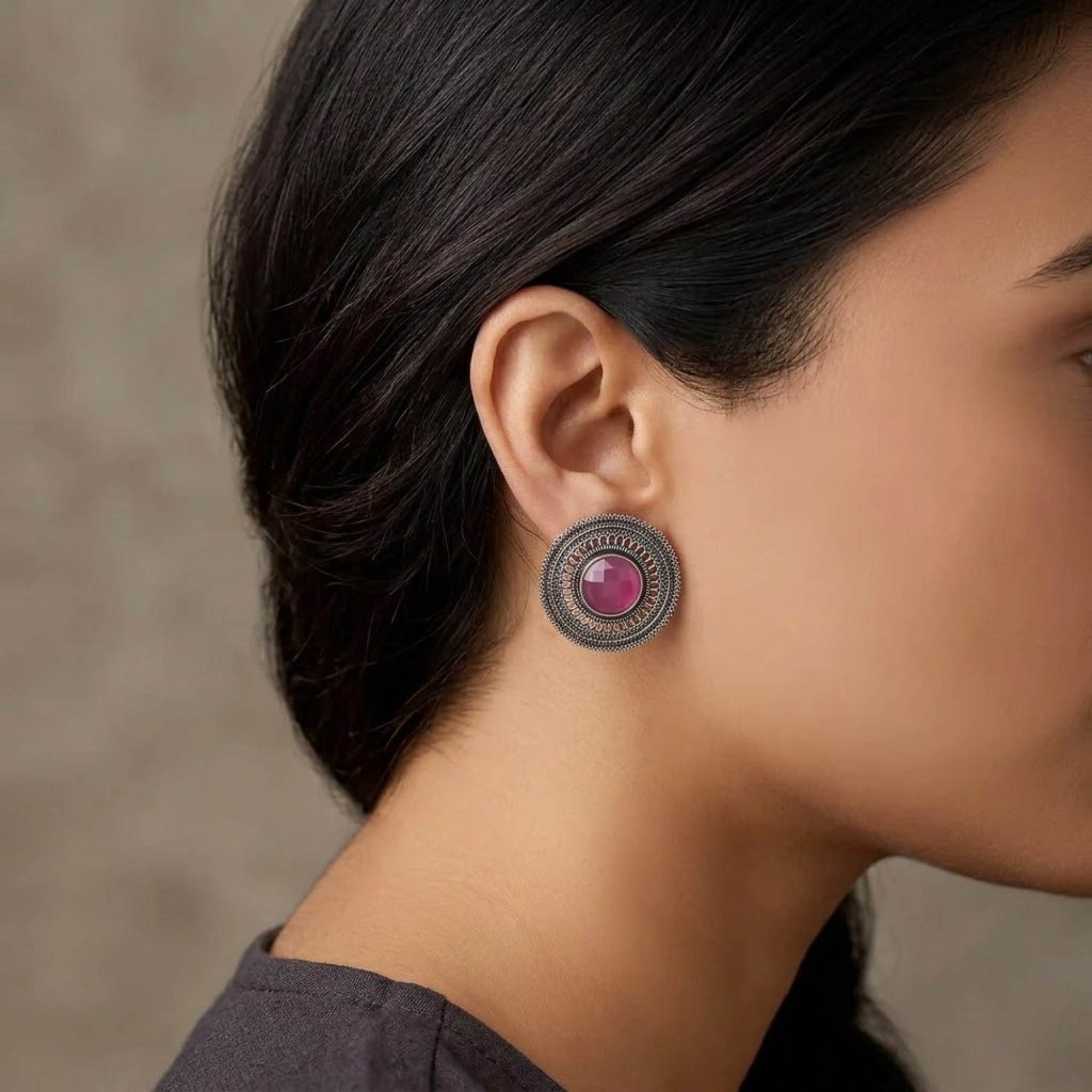 Pink oxidized metal stud earring with round stone and intricate circular design worn by woman