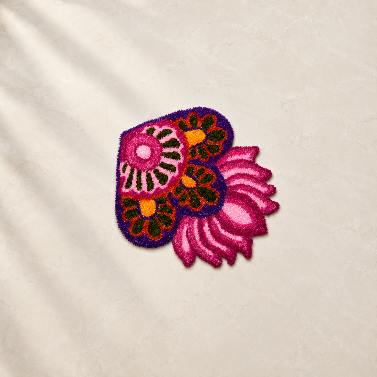 Pink and purple paisley floral rangoli with orange and green detailing