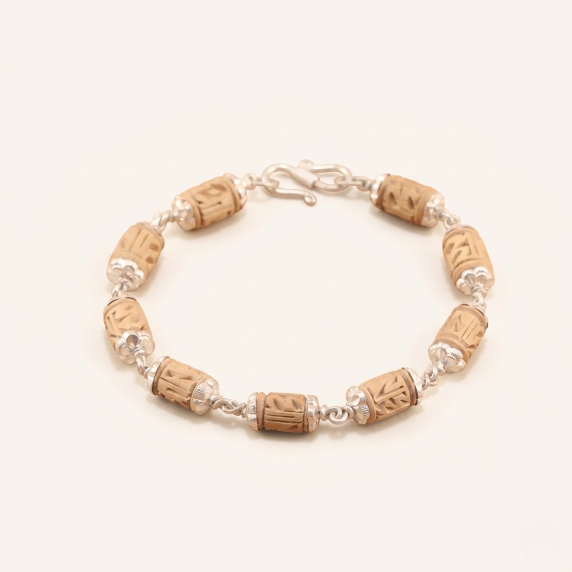 Close up flat lay of a pure silver bracelet featuring handcrafted carved Tulsi wood beads