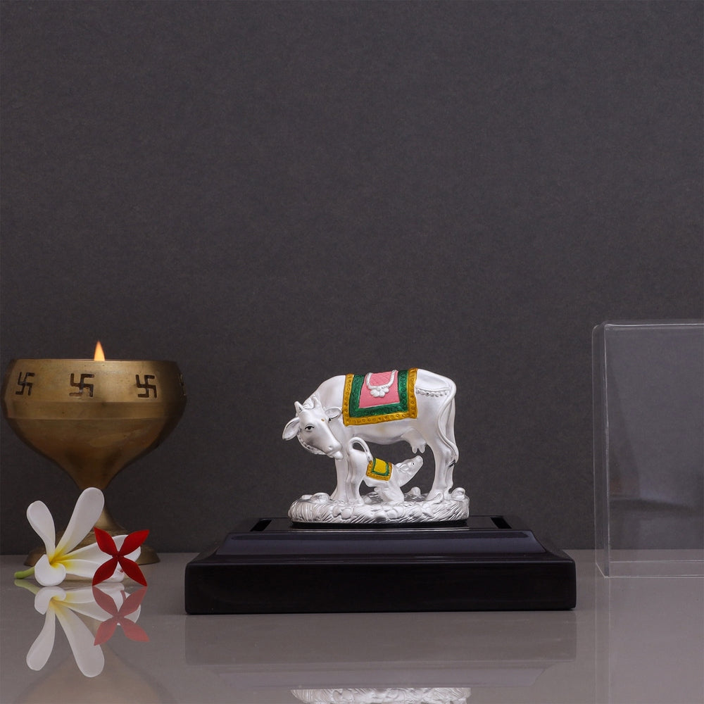 Pure silver Kamdhenu Cow with calf beautiful design showpiece displayed on a stand with a brass diya
