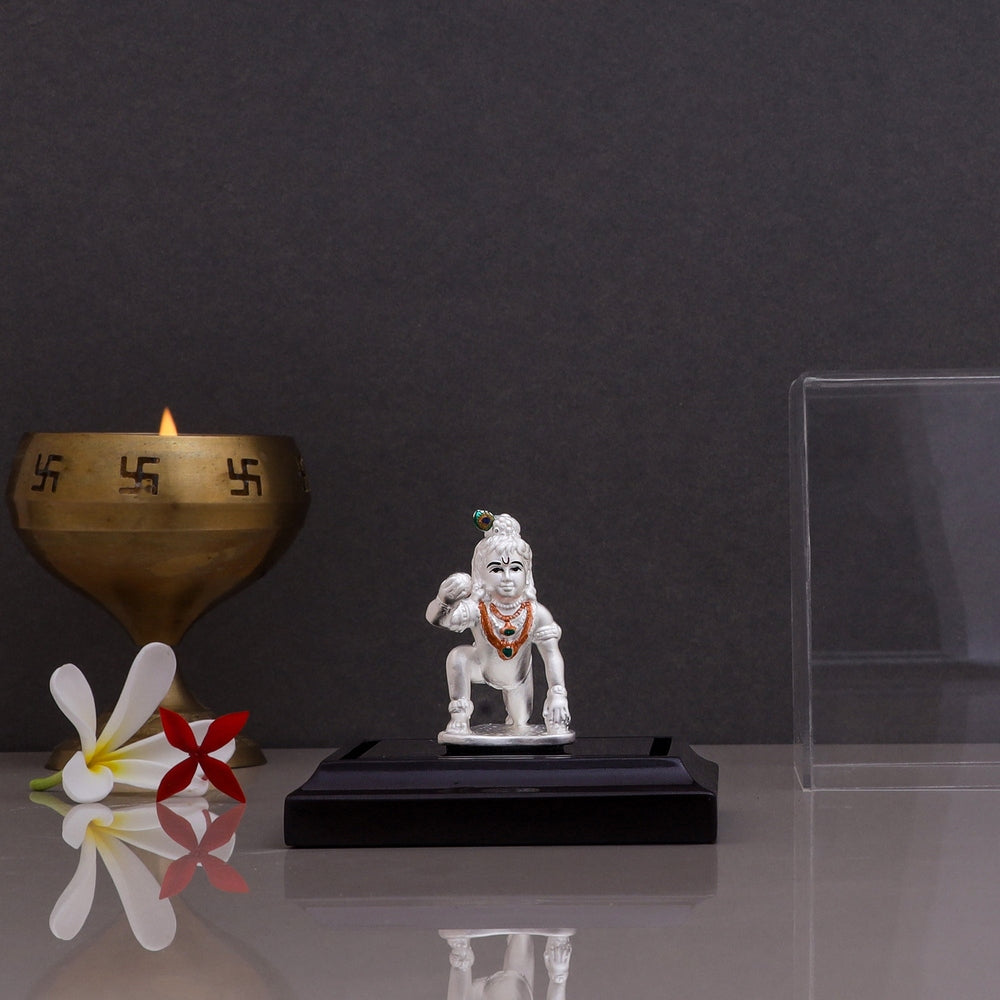 Pure silver Laddu Gopal idol of attractive design displayed on a black stand with a brass diya