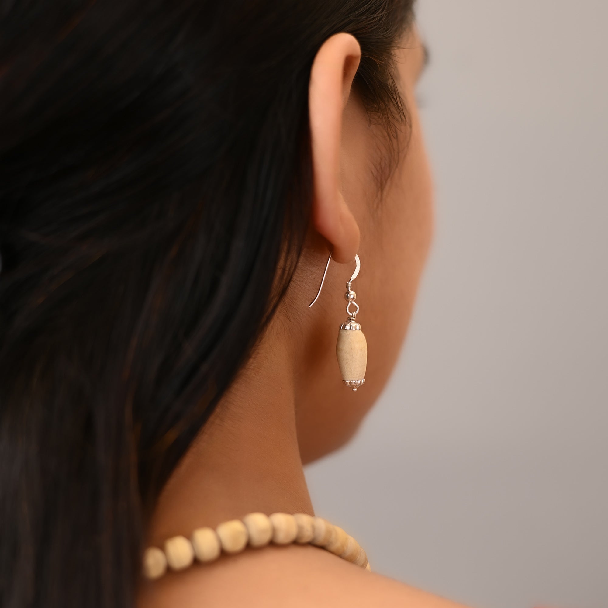 Woman wearing pure silver dangle earrings with oval shaped authentic Mathura Tulsi wood beads