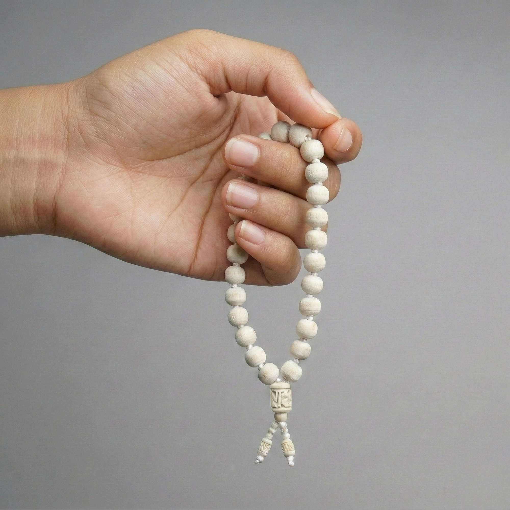 Hand holding a pure Tulsi japa mala with 27 smooth round beads