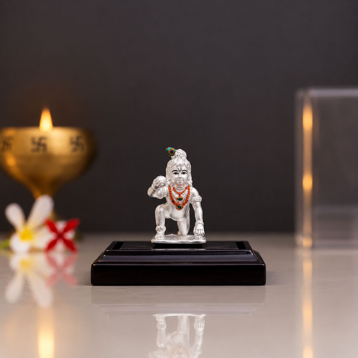 Silver Laddu Gopal idol in a kneeling pose with traditional ornaments and peacock feather