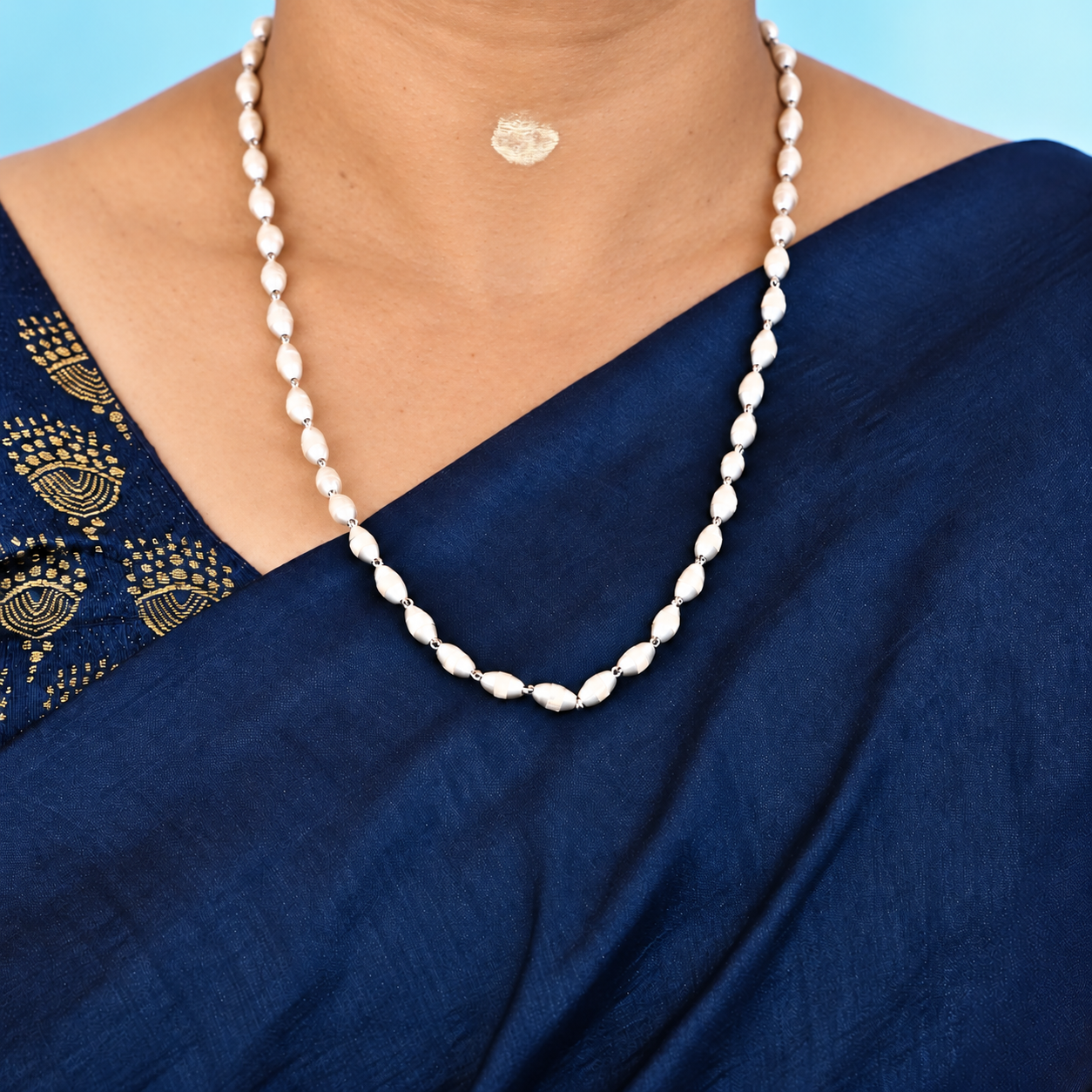Tulsi mala with pale oval beads and pure silver-toned links worn with a navy blue saree.