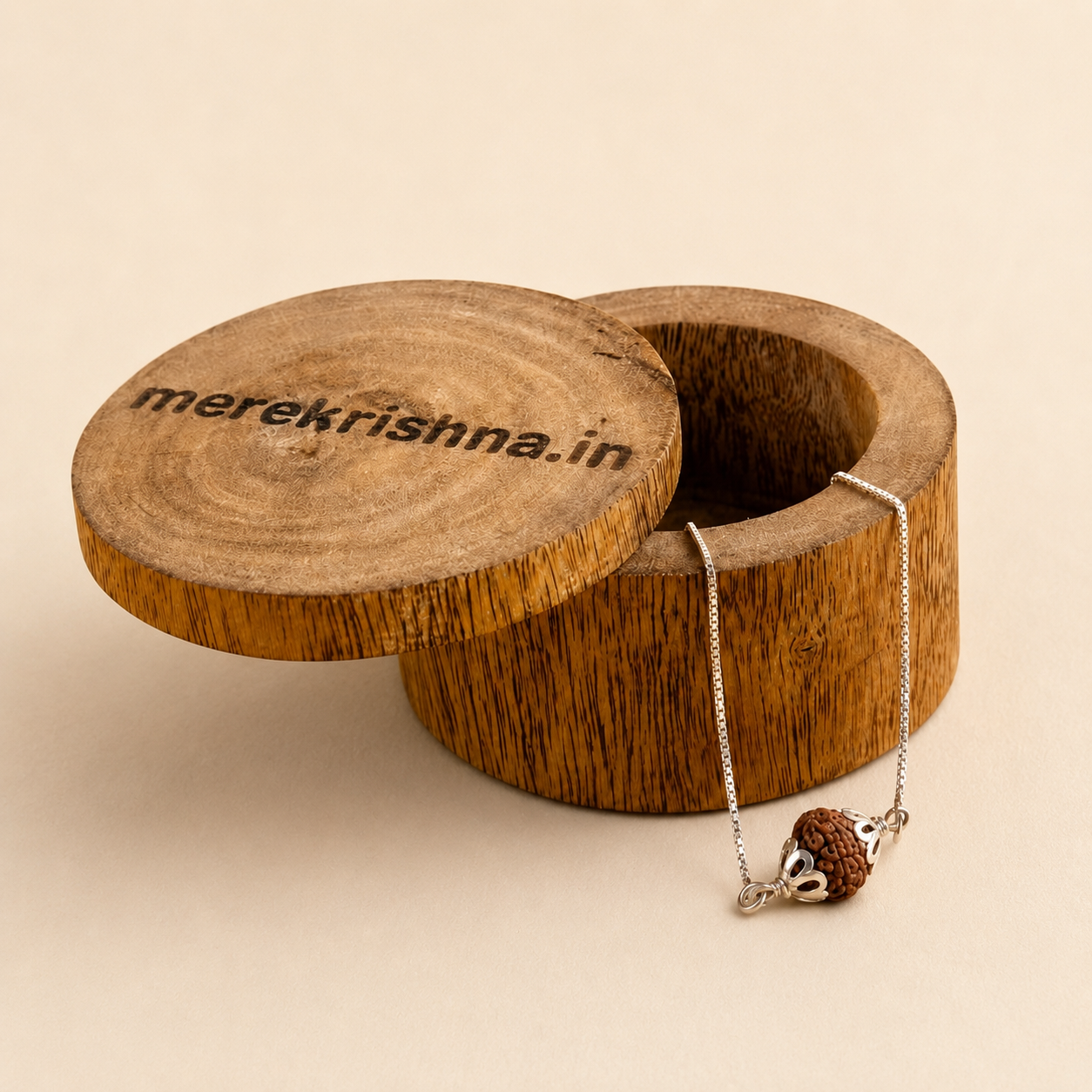 Pure silver capped Rudraksha chain bracelet rakhi for brother displayed on round wooden box