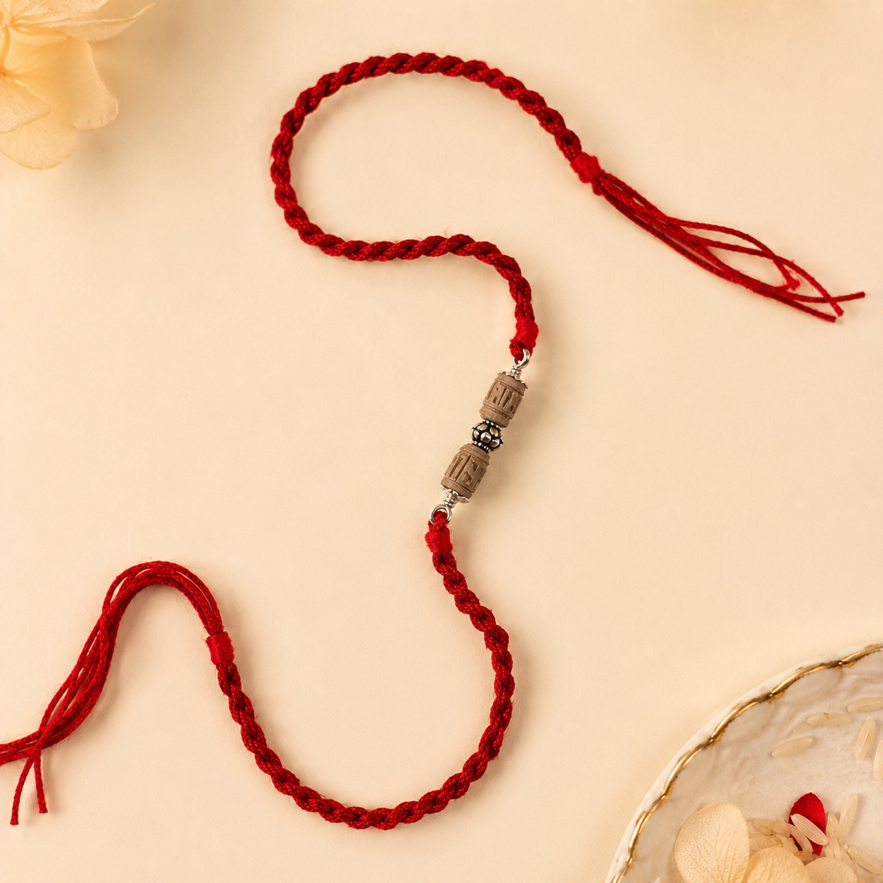 Pure silver carved Tulsi cylinder bead rakhi with silver capping on red thread flat lay view