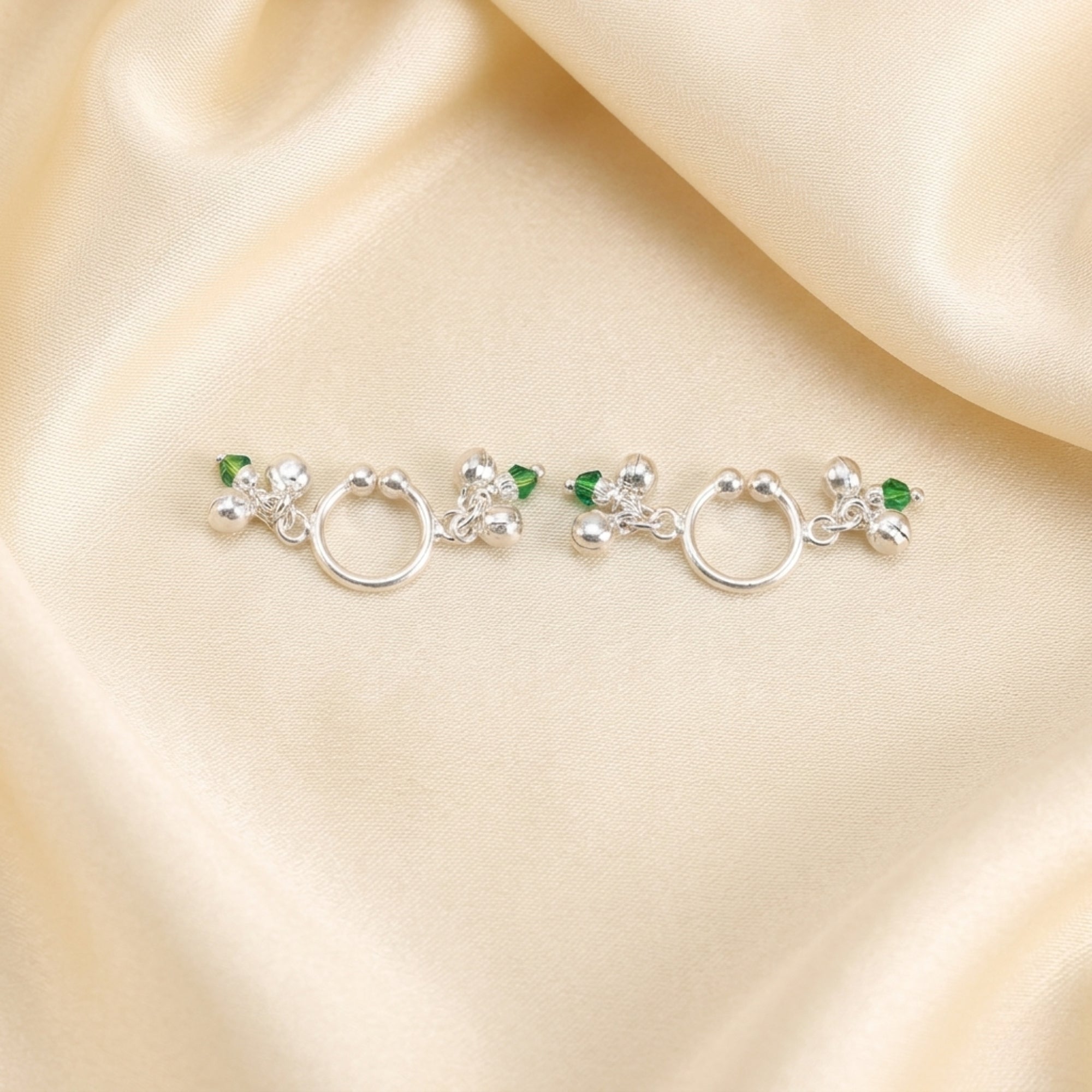 Pair of pure silver green Meenakari ghungroo payal anklets for Laddu Gopal displayed on cream silk fabric