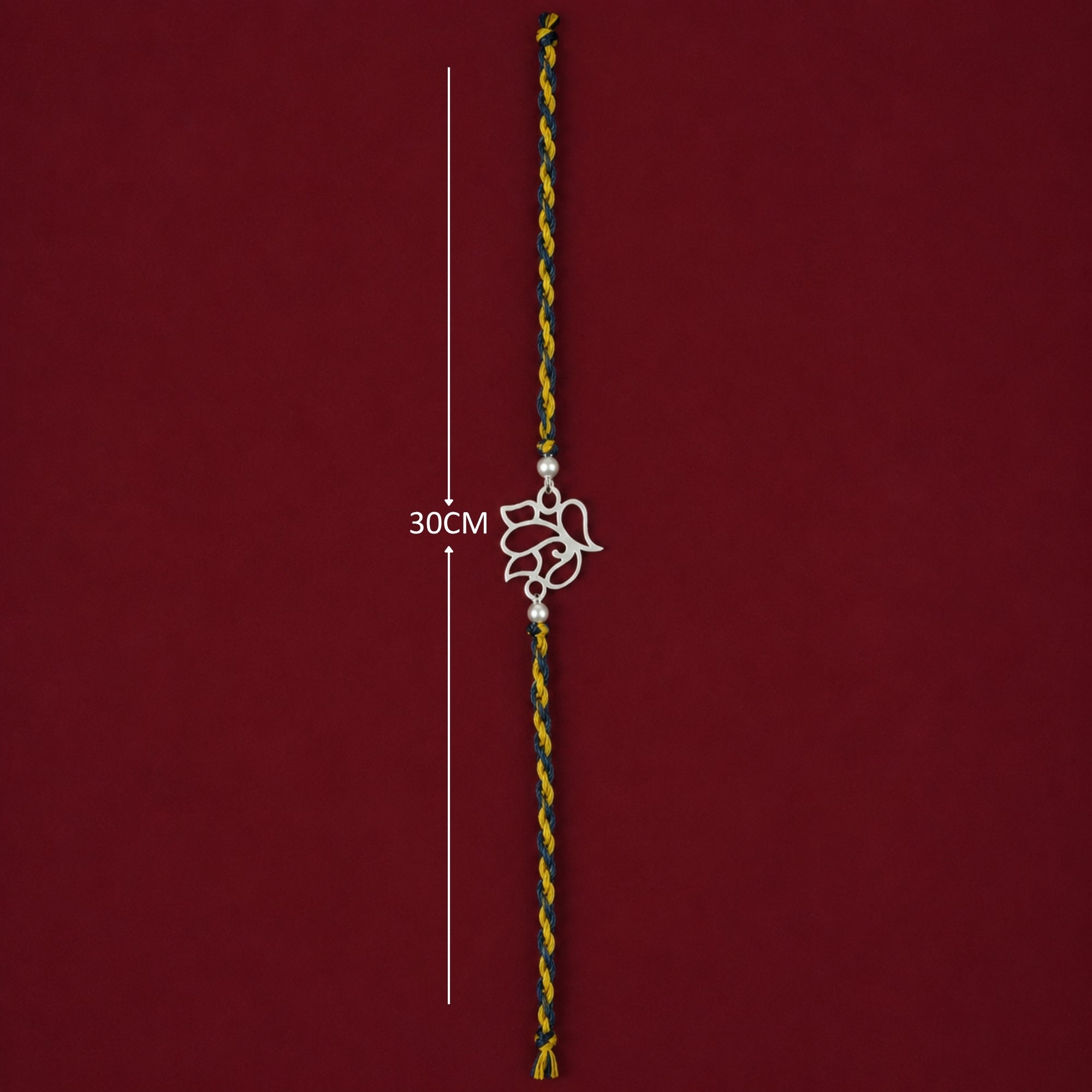 Full length 30cm layout showing thread and silver beads of openwork Ganesh rakhi