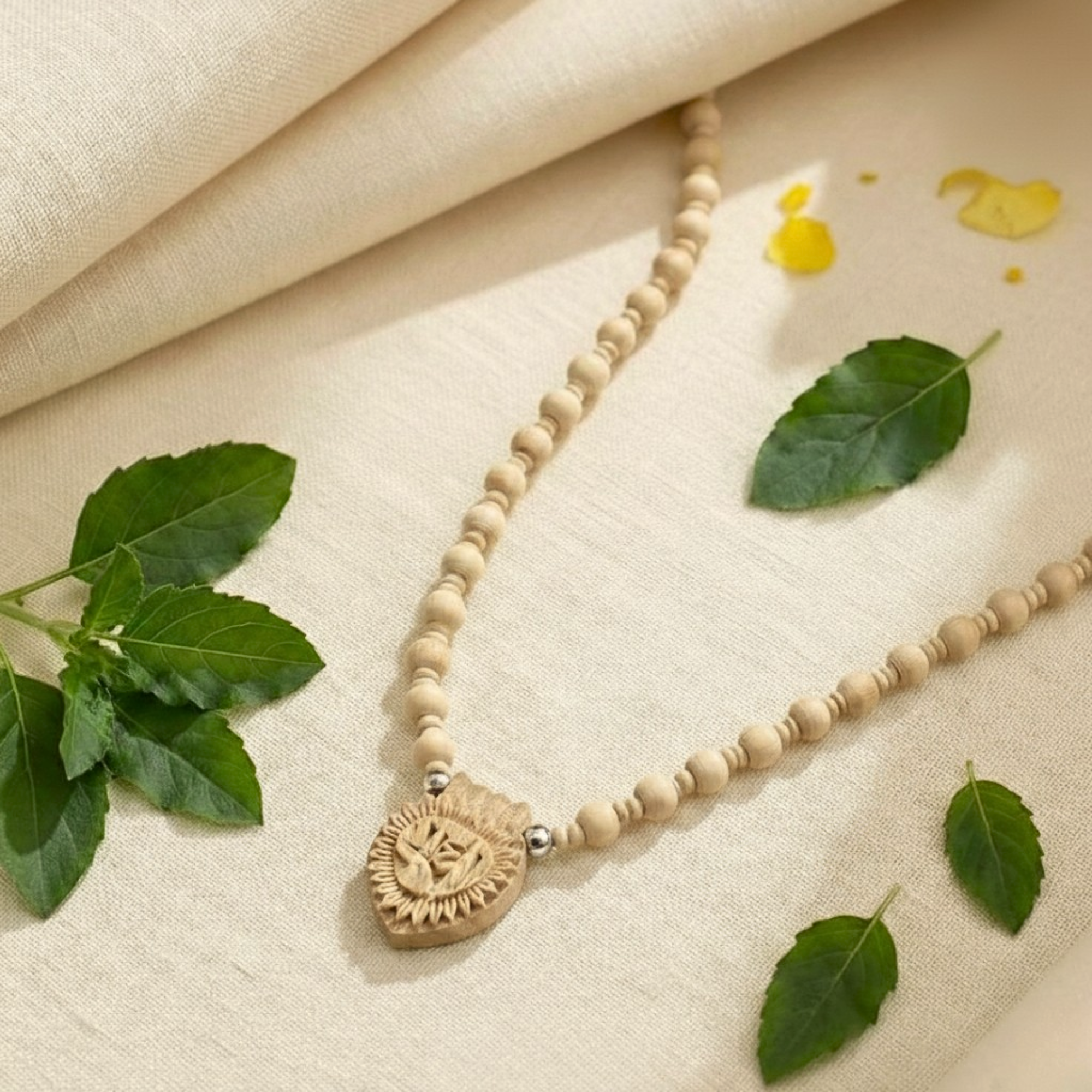 Silver Tulsi Mala necklace featuring a Radha name pendant laid on a surface with green leaves