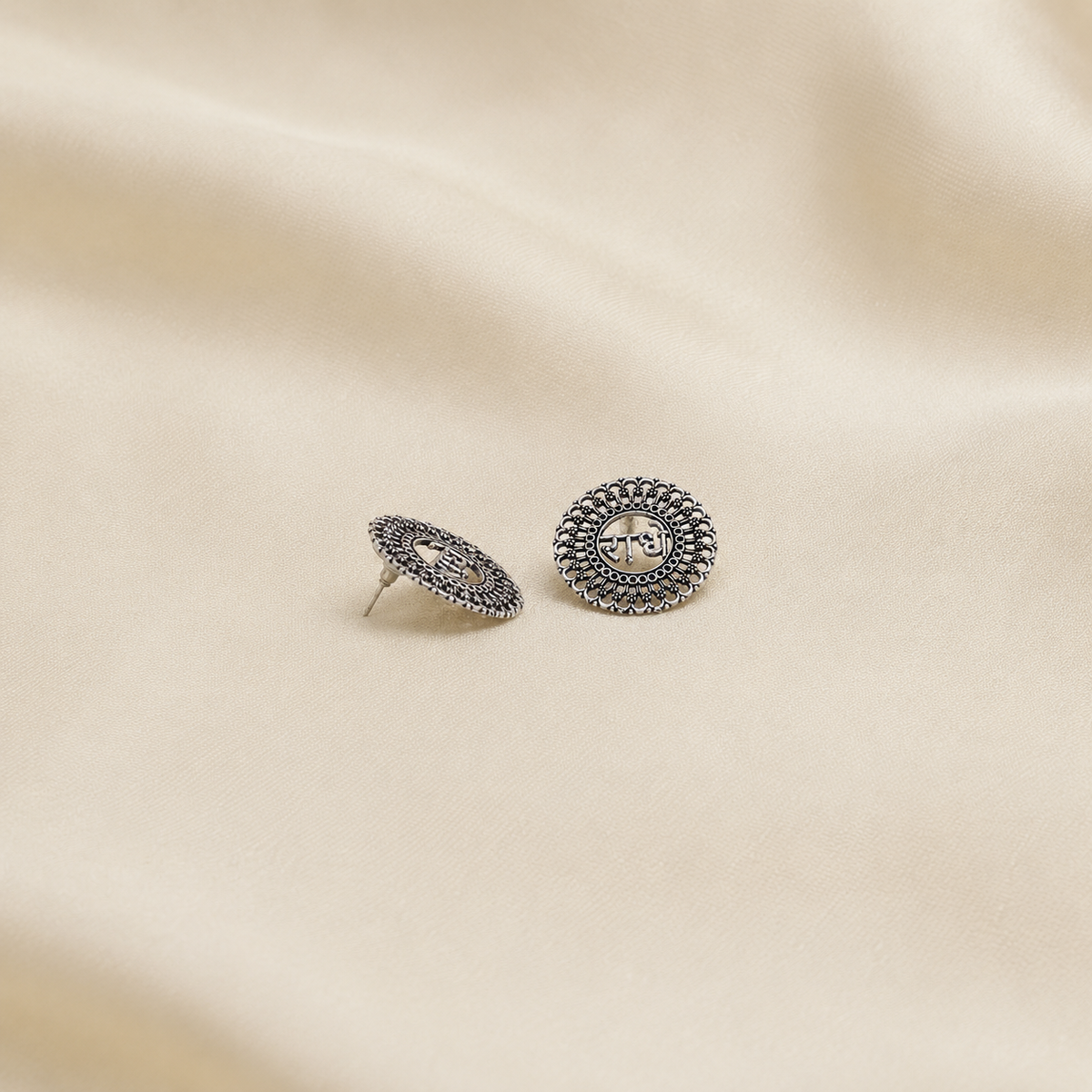 Radha oxidized metal stud earrings with round filigree design displayed on beige fabric