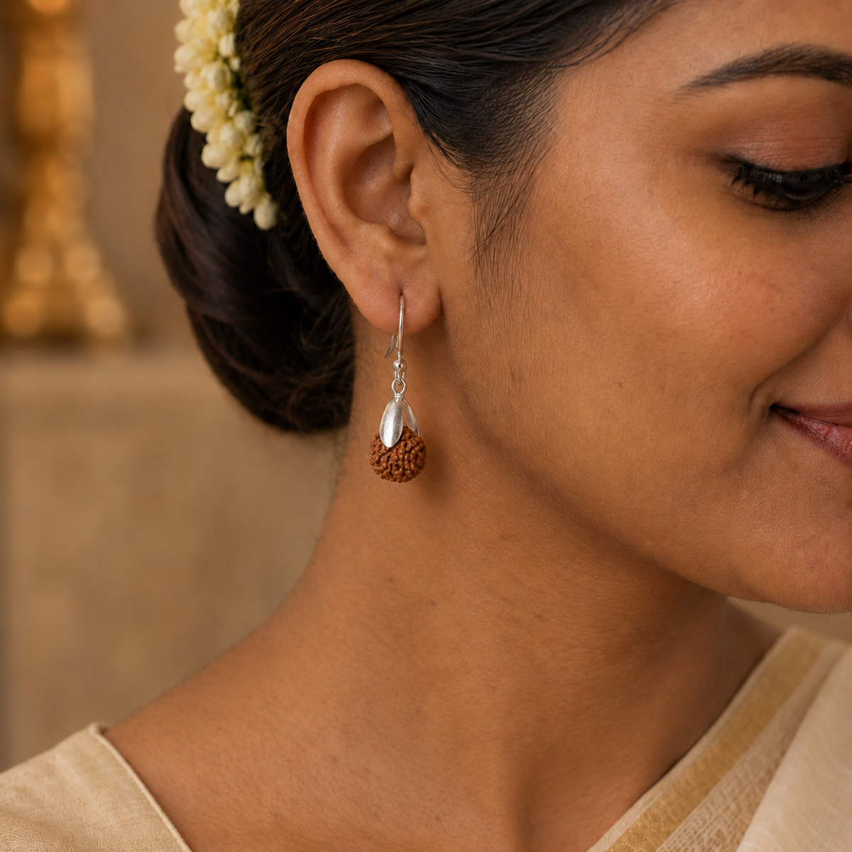 Rudraksha drop earring with a single brown bead, silver-toned leaf detail and hook worn on the ear.