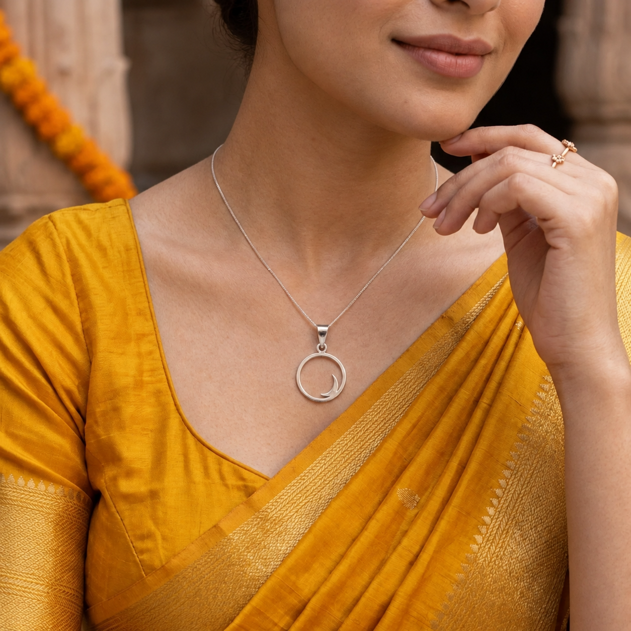 Woman in a mustard yellow saree wearing a silver crescent moon pendant necklace.