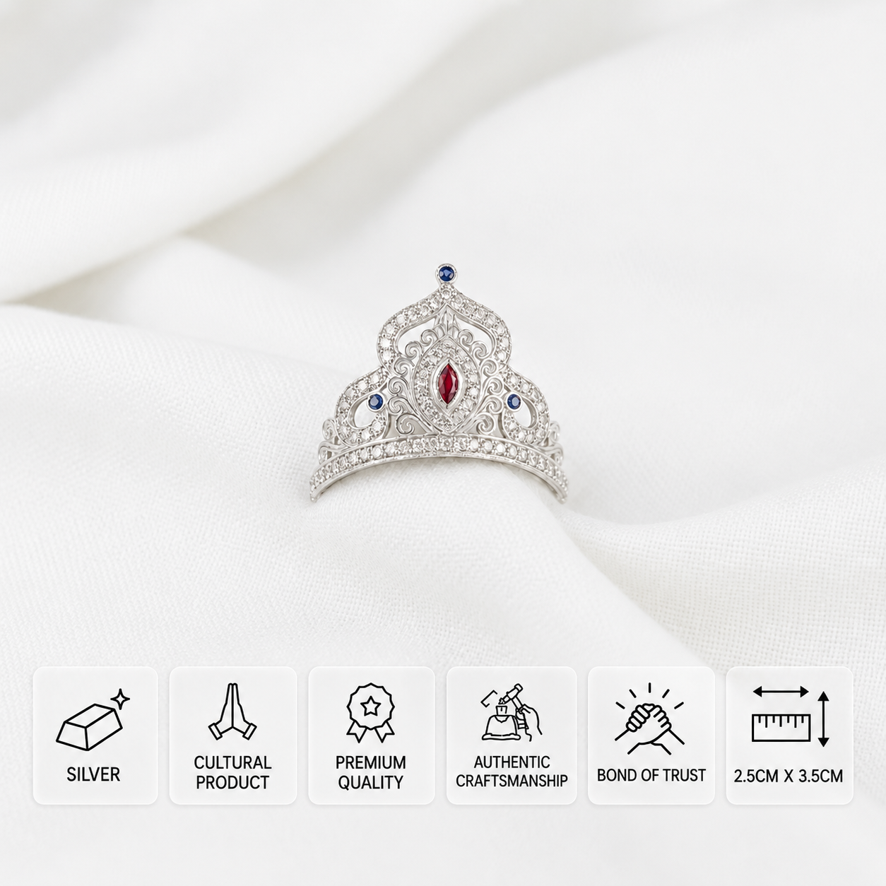 Silver idol crown with red, blue and clear stones, with 2.5 × 3.5 cm dimensions.