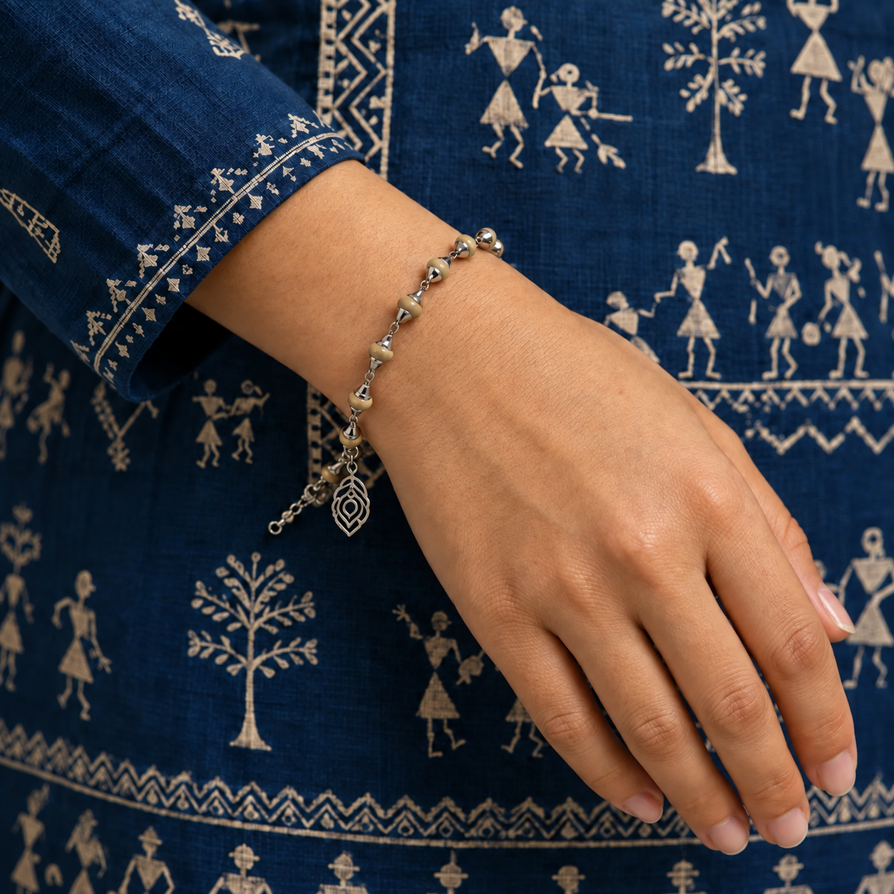 Tulsi bead bracelet with silver-toned caps, chain links and a dangling peacock feather charm worn on a wrist.