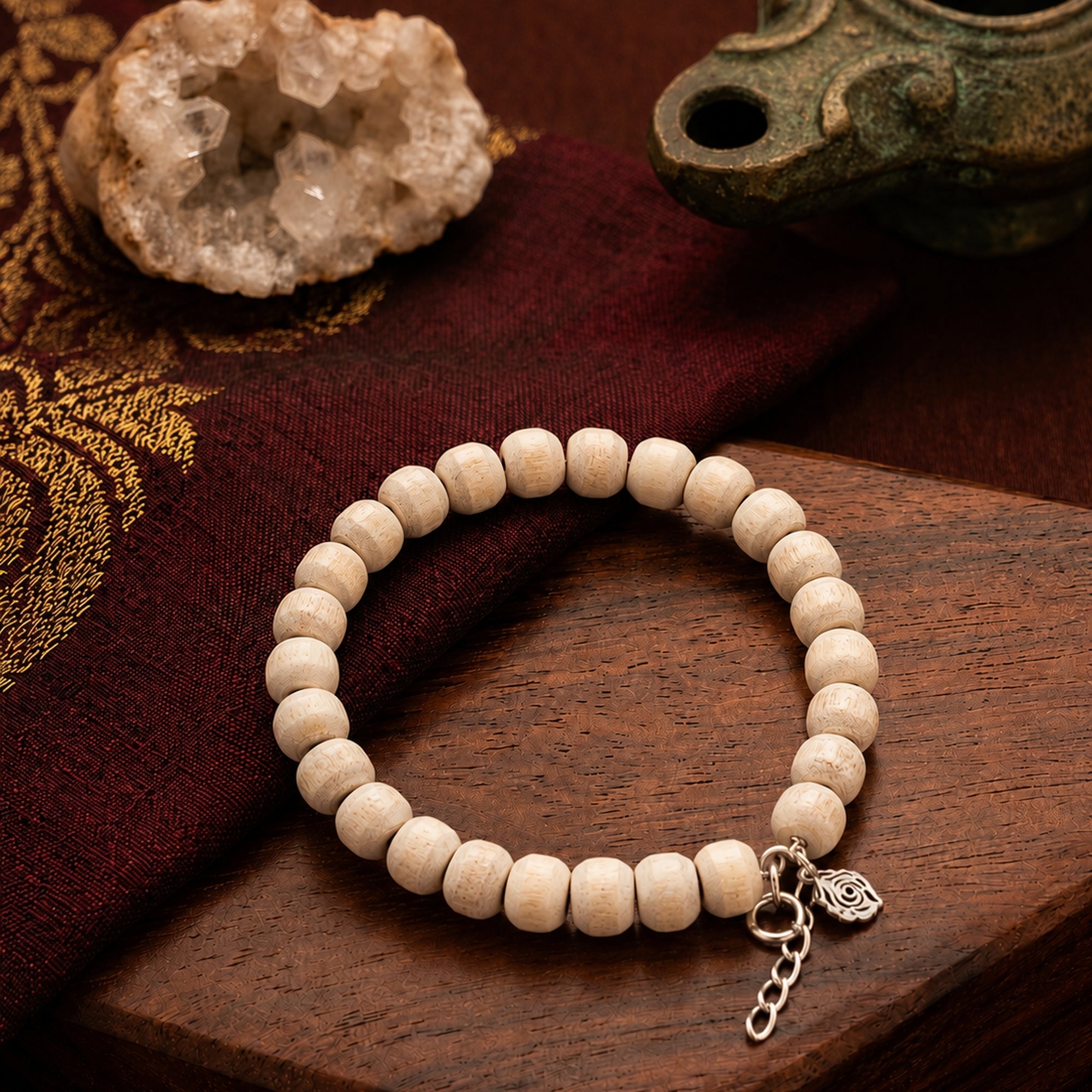 Silver bracelet featuring authentic Tulsi wood beads placed on a traditional cloth next to crystals