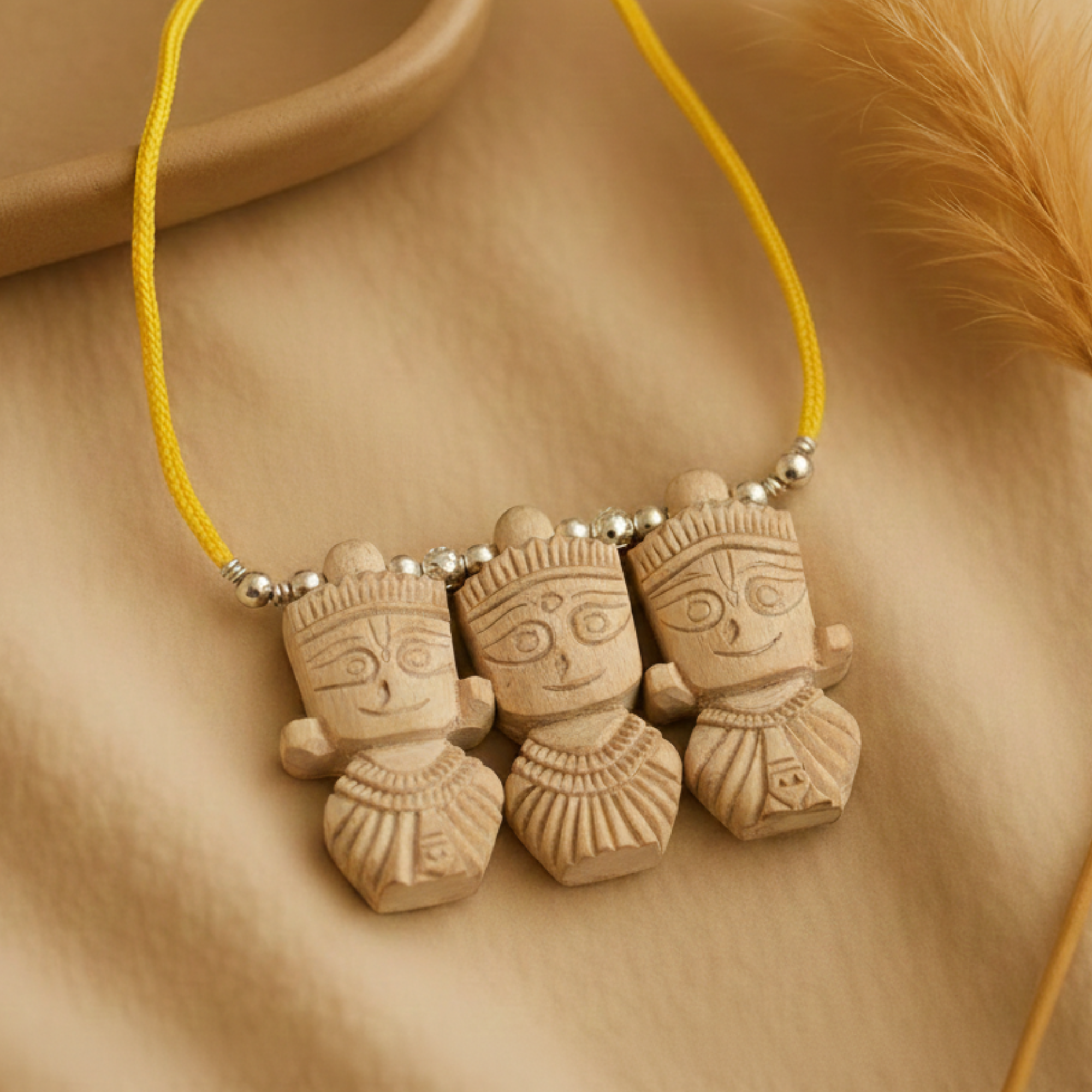 Person wearing a silver pendant featuring carved Tulsi wood figures of Jagannath, Balbhadra, and Subhadra