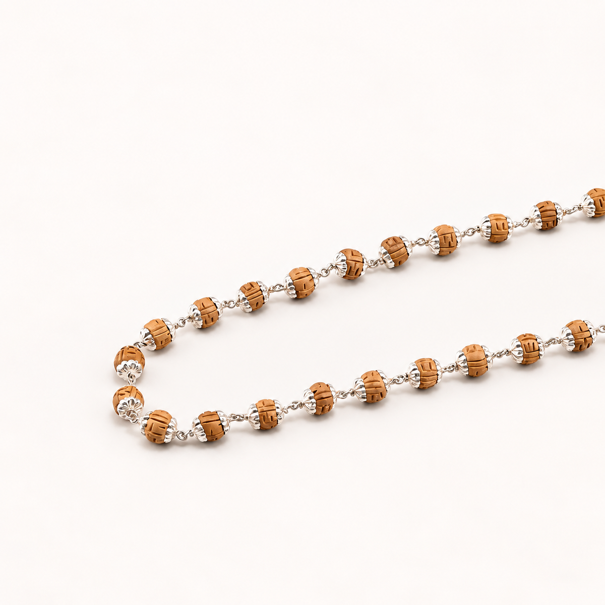 Silver Tulsi mala with natural wooden beads, detailed silver caps and linked chain on a clean light background.