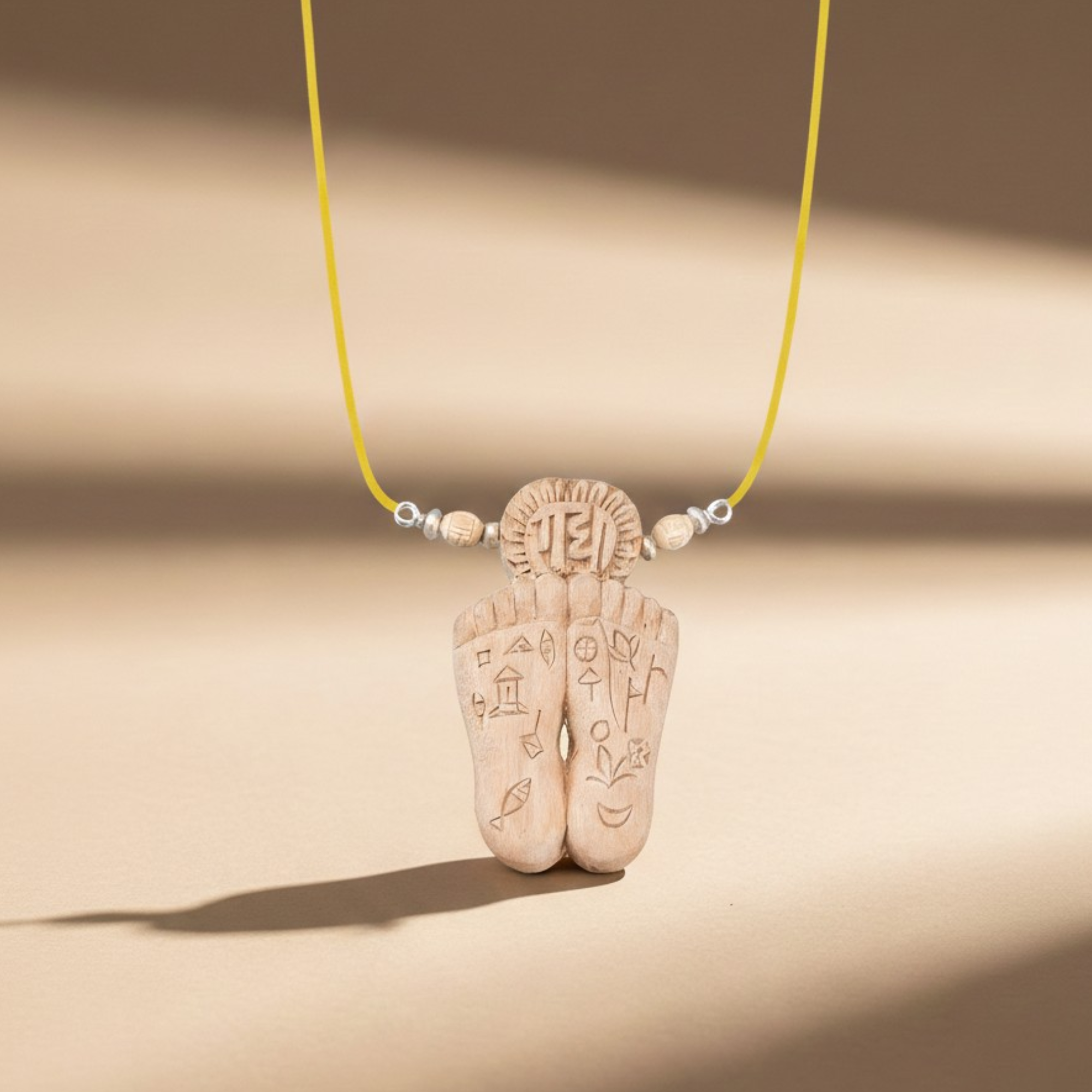 Person wearing a silver pendant featuring sacred Radha Charan lotus feet carved on Tulsi wood