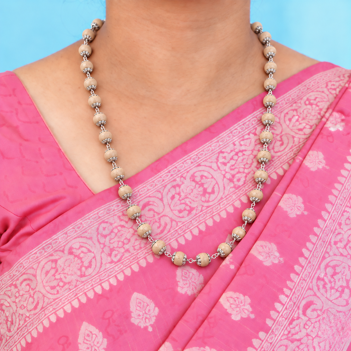 Woman in a pink saree wearing a Tulsi wood bead mala with silver floral bead caps and linked silver loops.